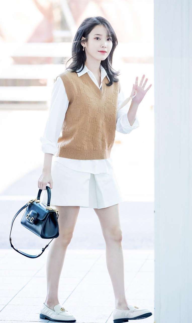 iu李知恩机场街拍,身穿白色衬衫77咖色针织背心,搭配半裙与乐福鞋