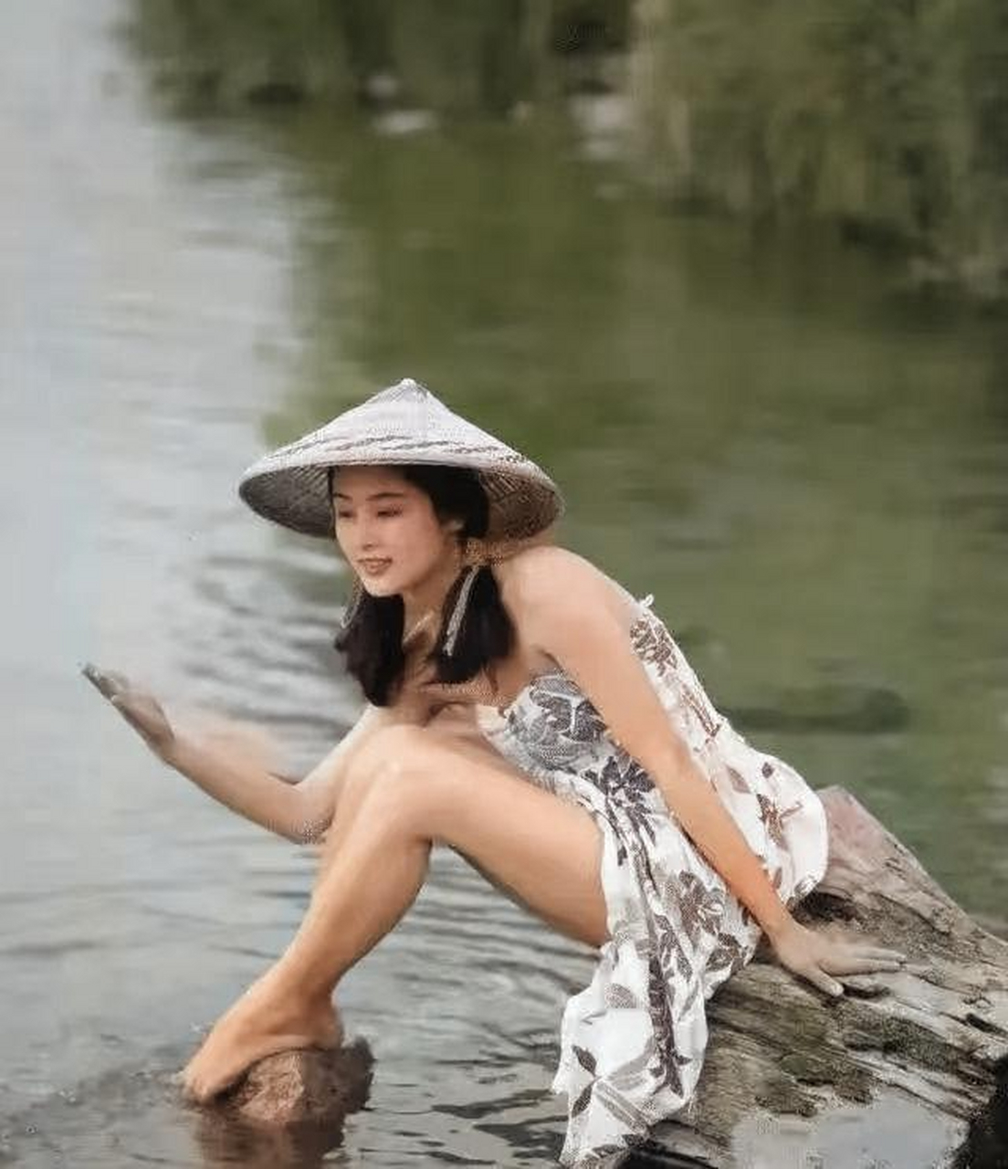 陈红年轻时候的绝美留影,照片中她穿着一条吊带印花长裙,戴着一顶斗笠