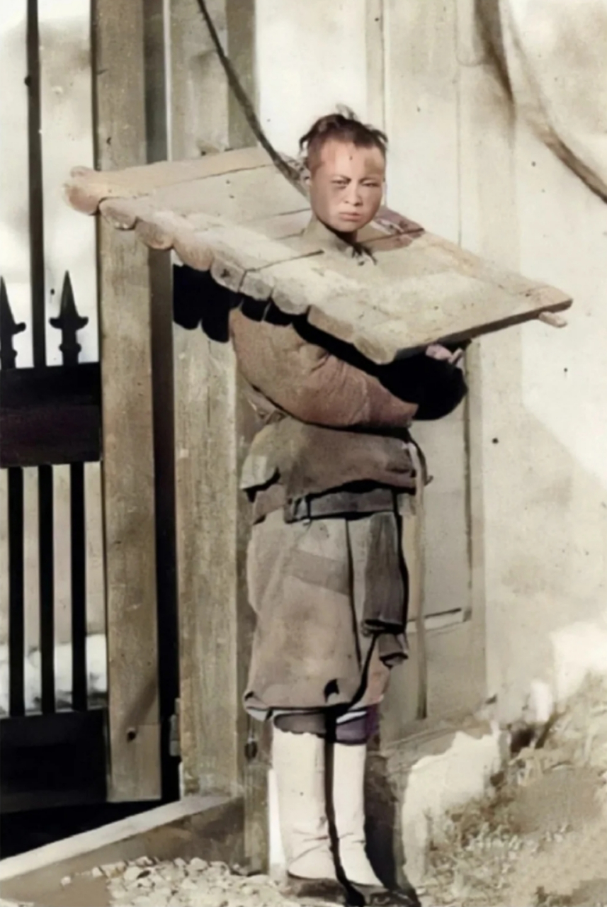 这是1903年,一个囚犯身上戴着几十斤重的枷锁,怒视镜头,不知他所犯