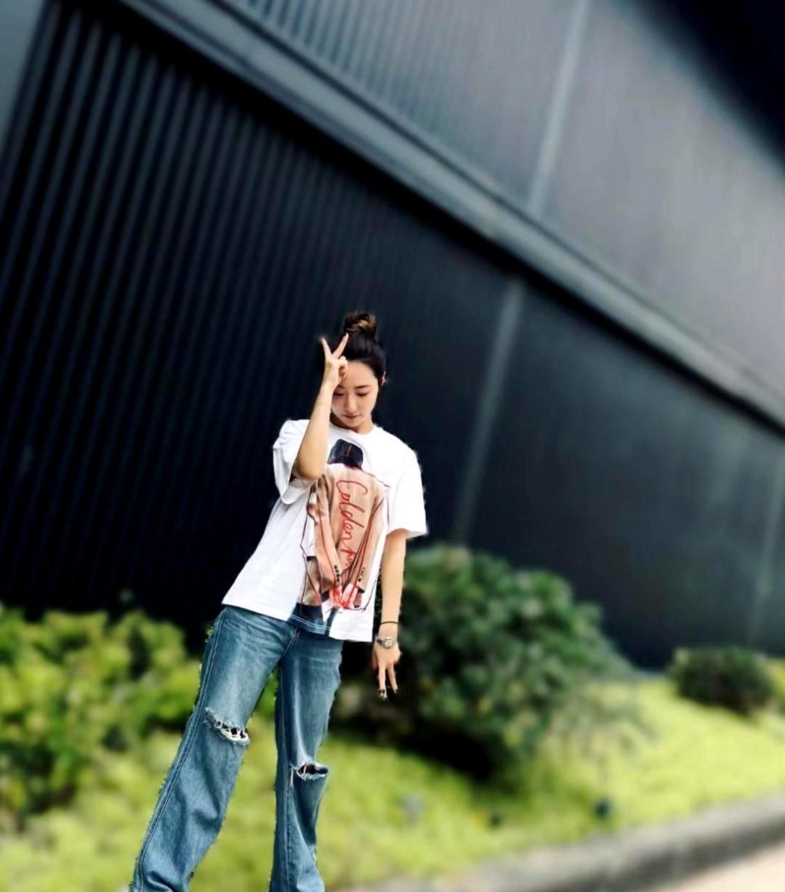 白冰在小区花园拍日常照,穿着白t恤和牛仔裤显得年轻时尚,身材保持得