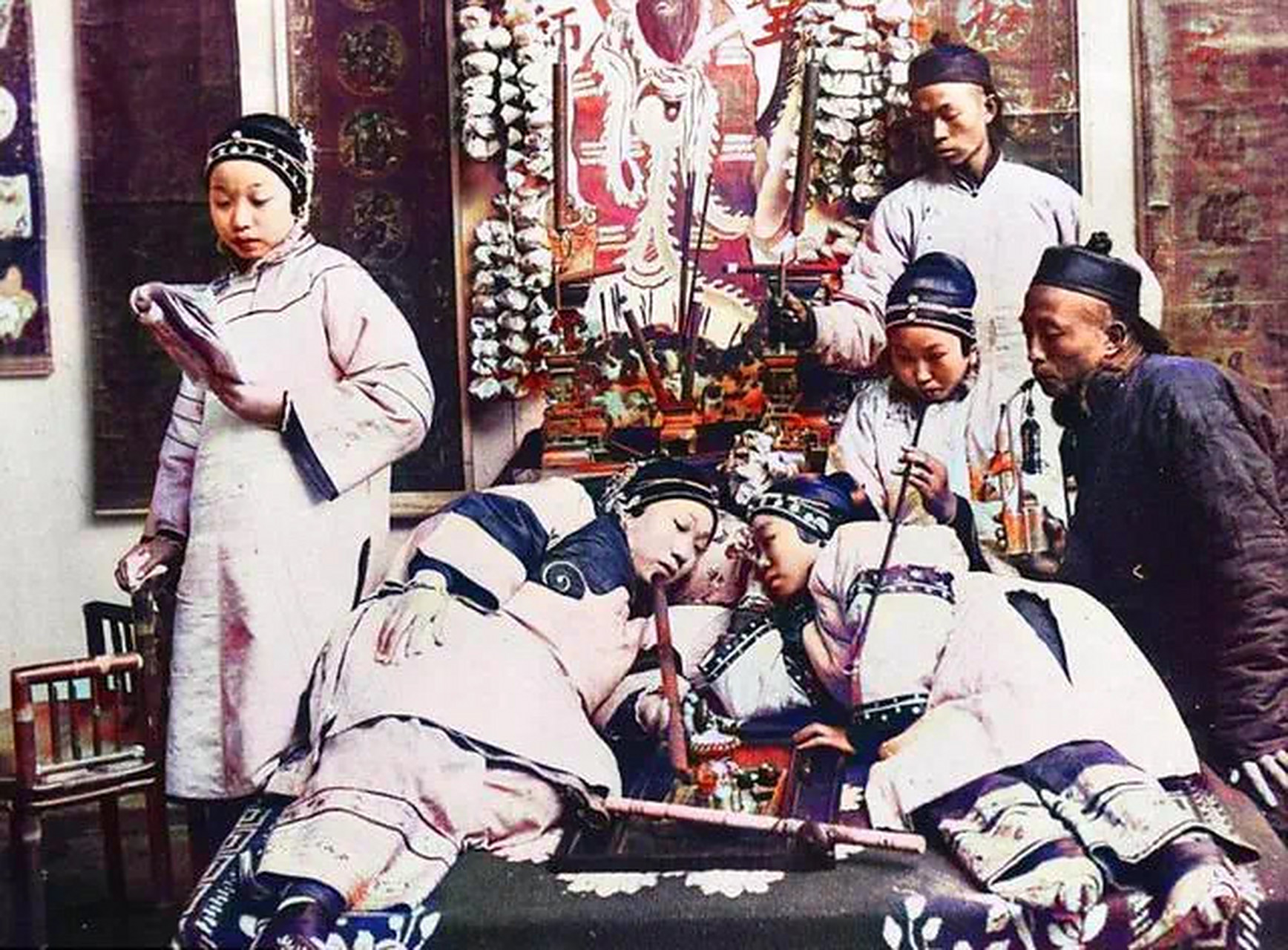 这里是一个烟管,两个正在吸食鸦片的女子,其他人在旁边看着她们,也有