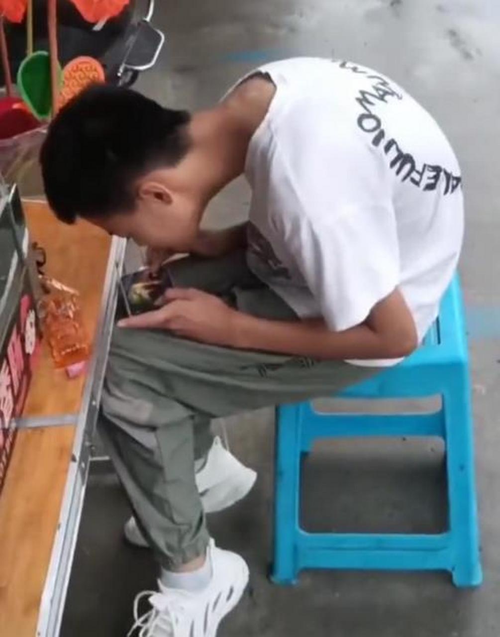 一个男孩坐在椅子上低头玩手机,颈部已经严重变形,让人看着非常心疼!