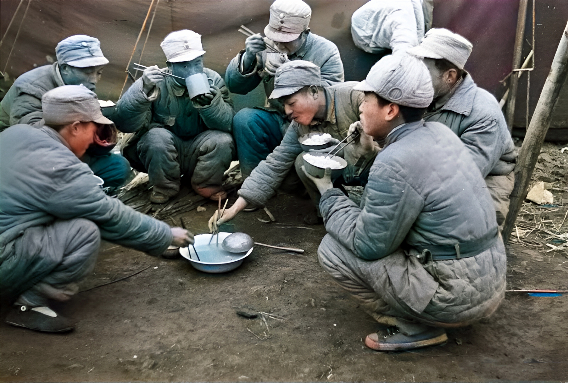 一名炊事班的士兵正用大勺从一口大锅里向外舀菜