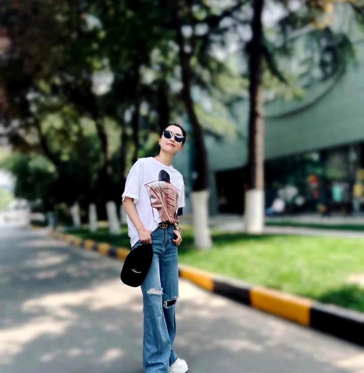 白冰在小区花园拍日常照,穿着白t恤和牛仔裤显得年轻时尚,身材保持
