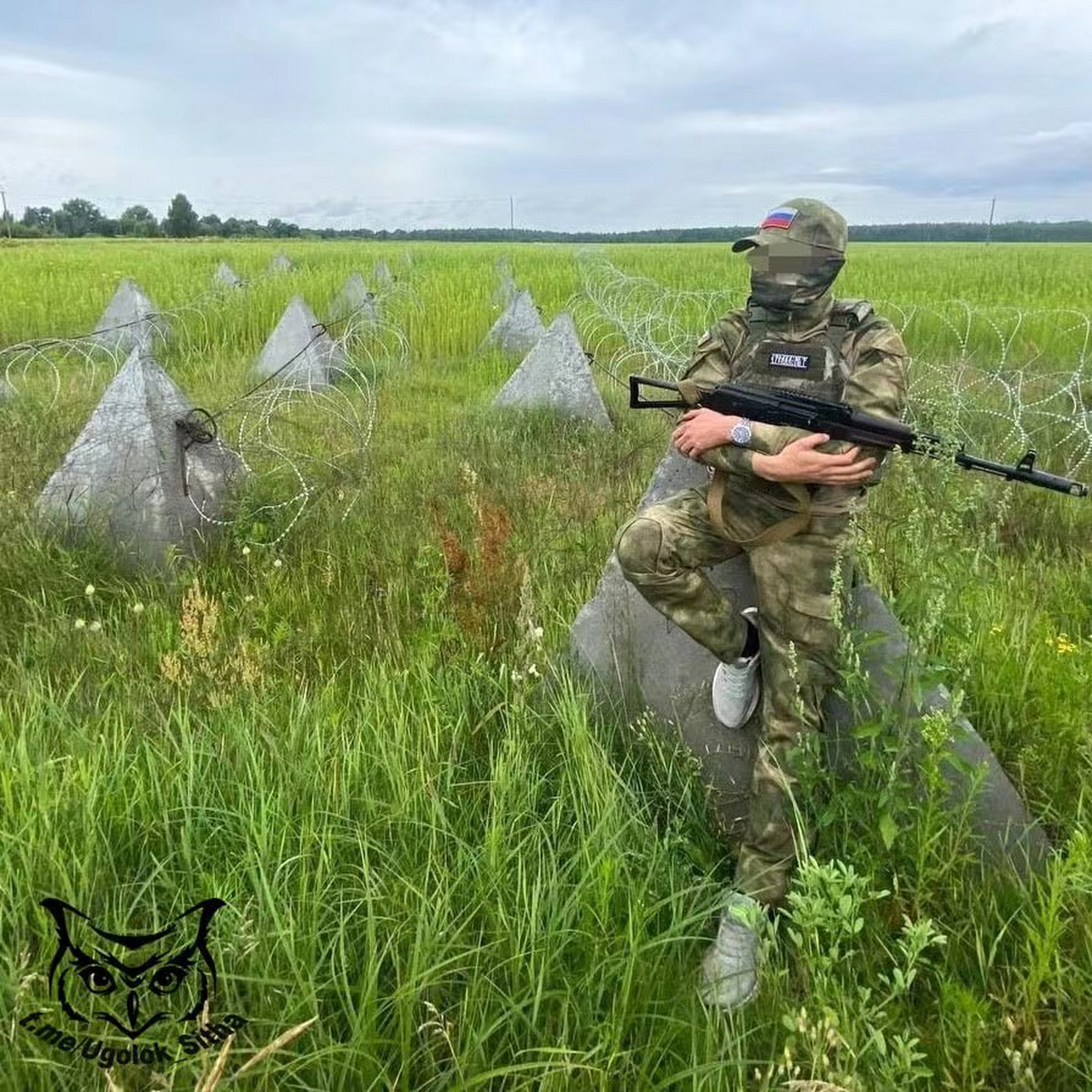 一名俄军士兵正坐在"龙牙"反坦克障碍物上,其脚上的白色运动鞋显得很