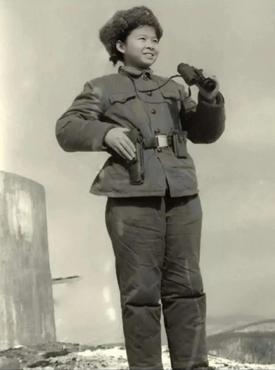 上个世纪70年代,一名穿着军服的小女孩手持望远镜,腰挂手枪的照片引起