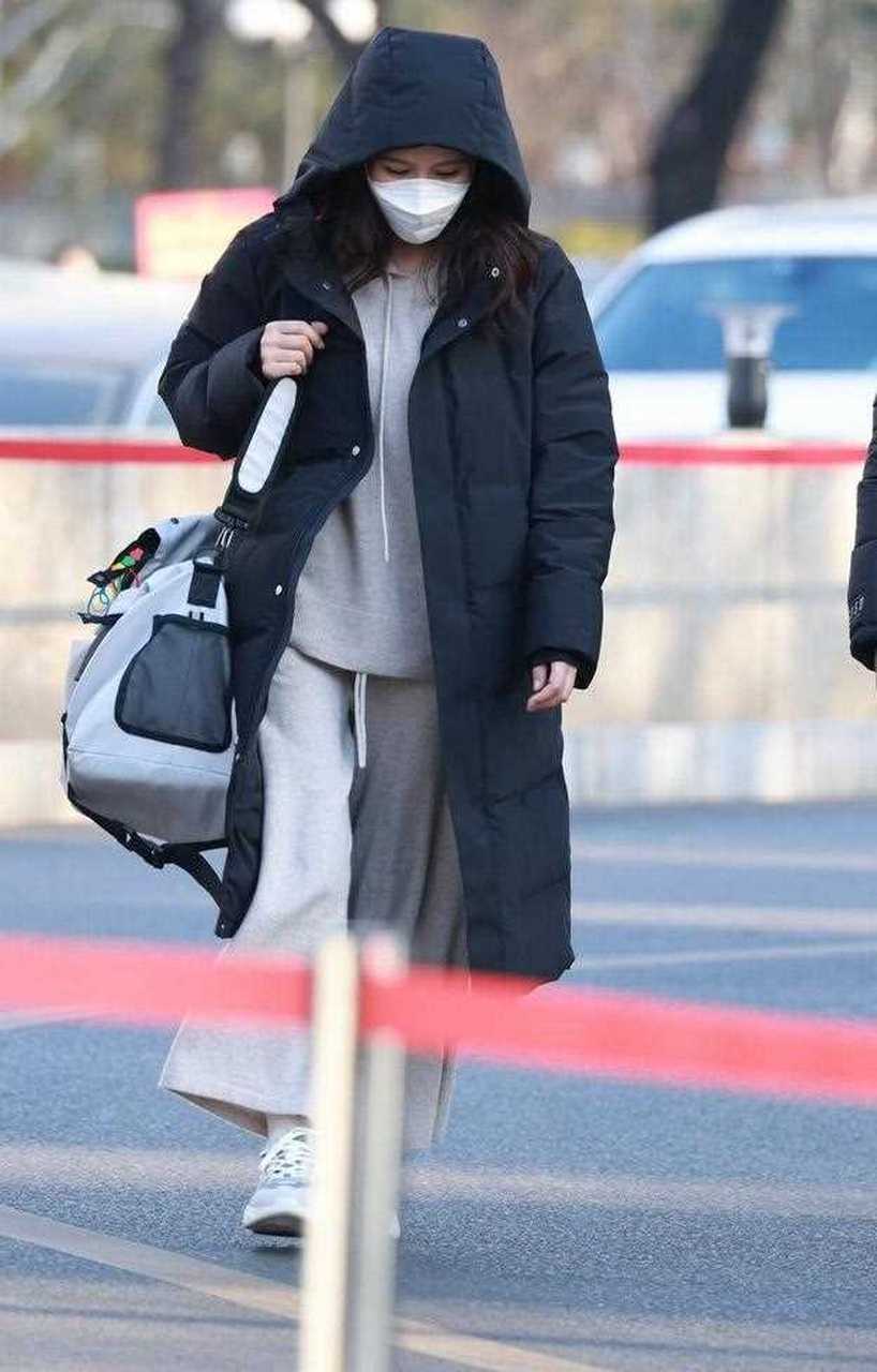 热依扎最新机场照来了,她穿了一件黑色的长款连帽大衣,内搭一件浅灰色