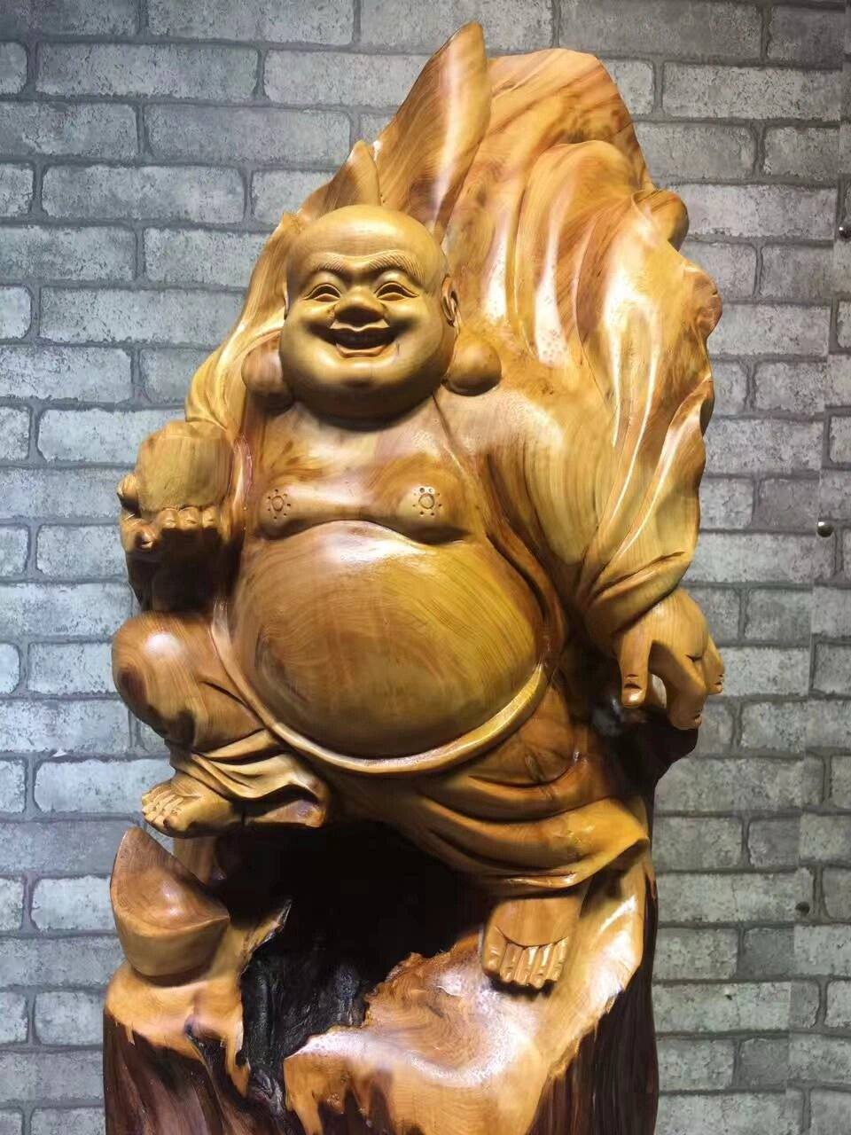 这款雕像以优质的木材精雕细琢而成,展现了弥勒佛的大肚腩和愉悦的