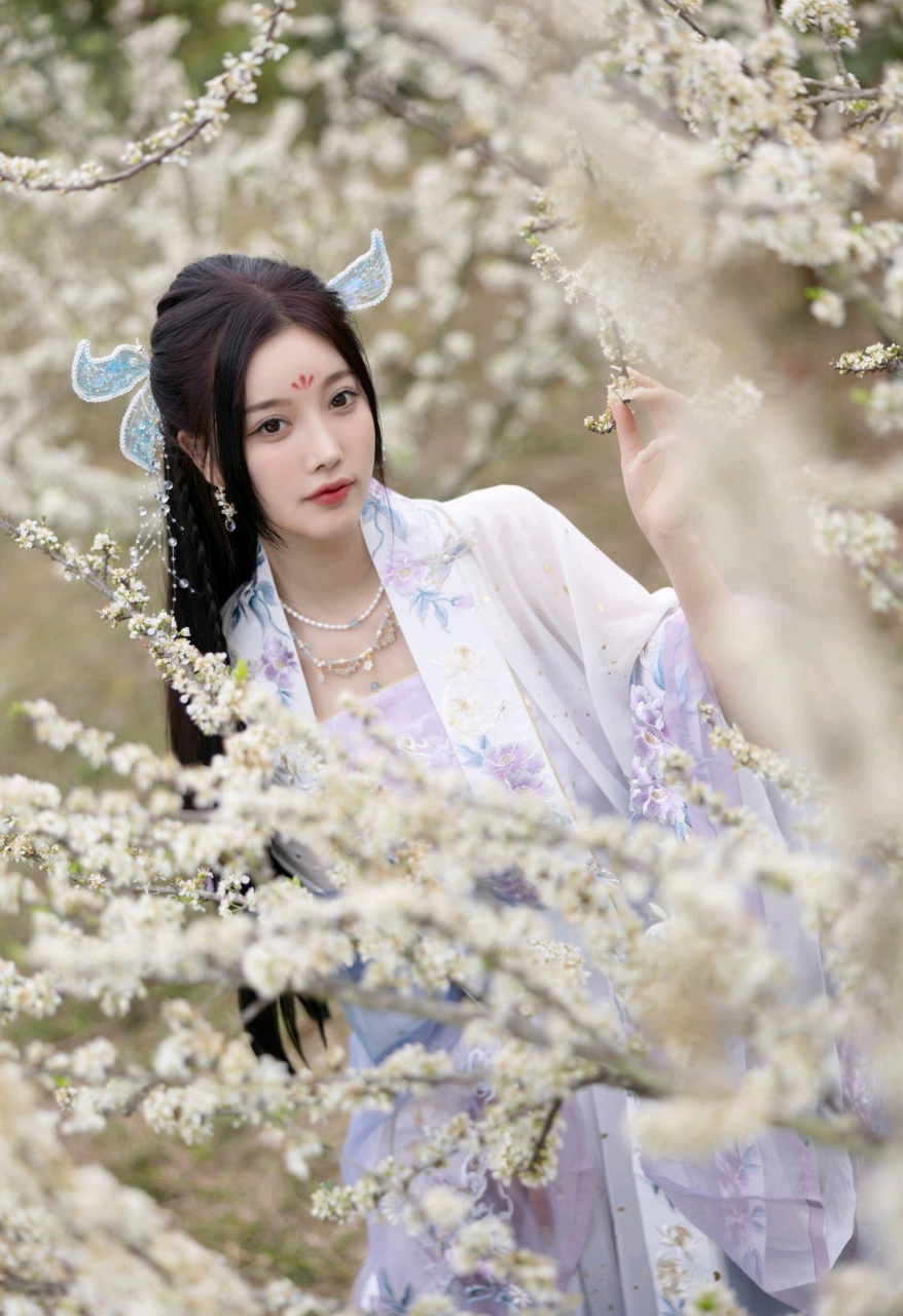 她身着华丽的古装连衣女裙,裙子的配色以淡紫色,白色,淡蓝色和粉色等