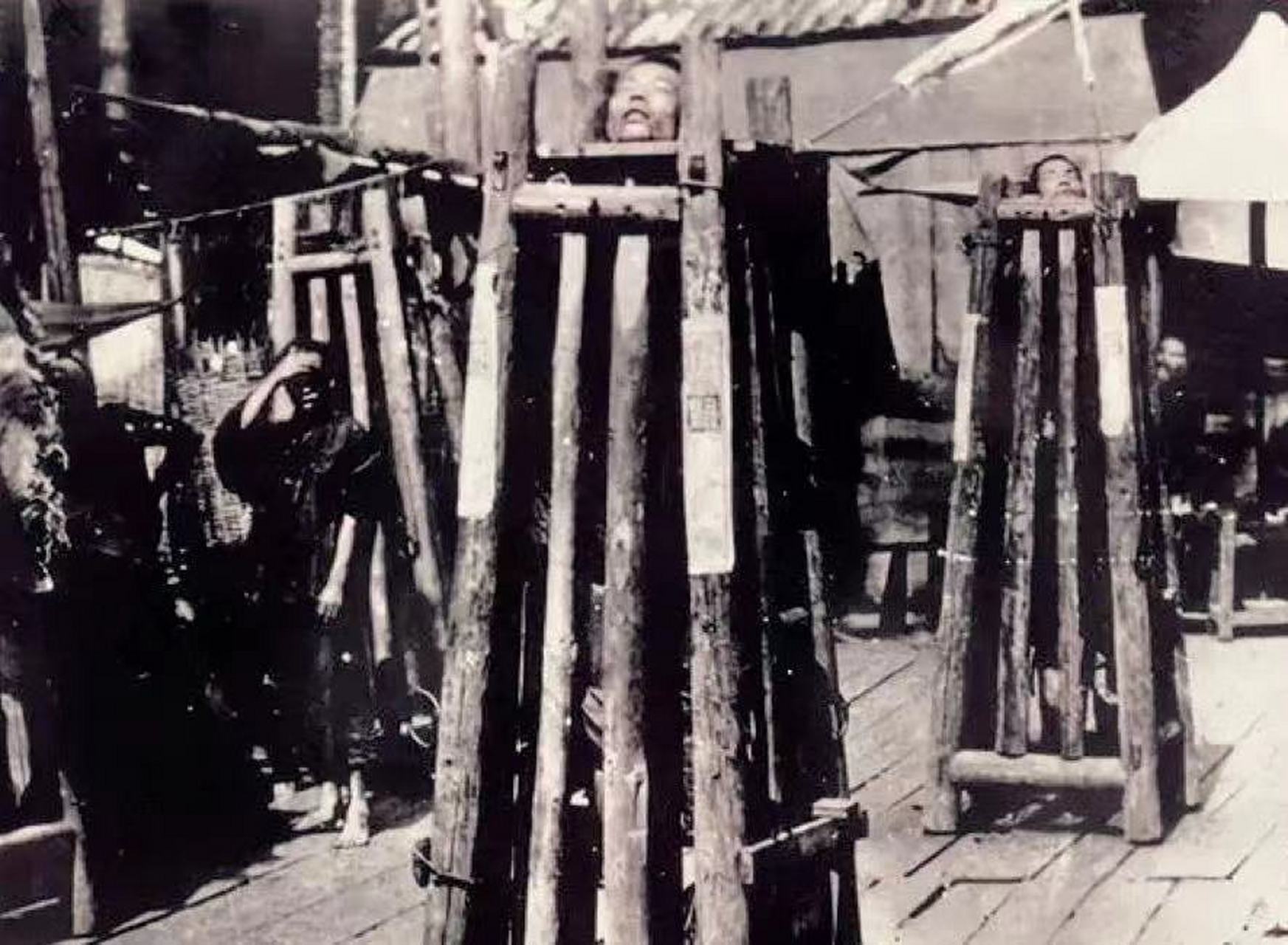 晚清时期,两名囚禁在站笼中的犯人照片,镜头中的他们显然经过长时间的