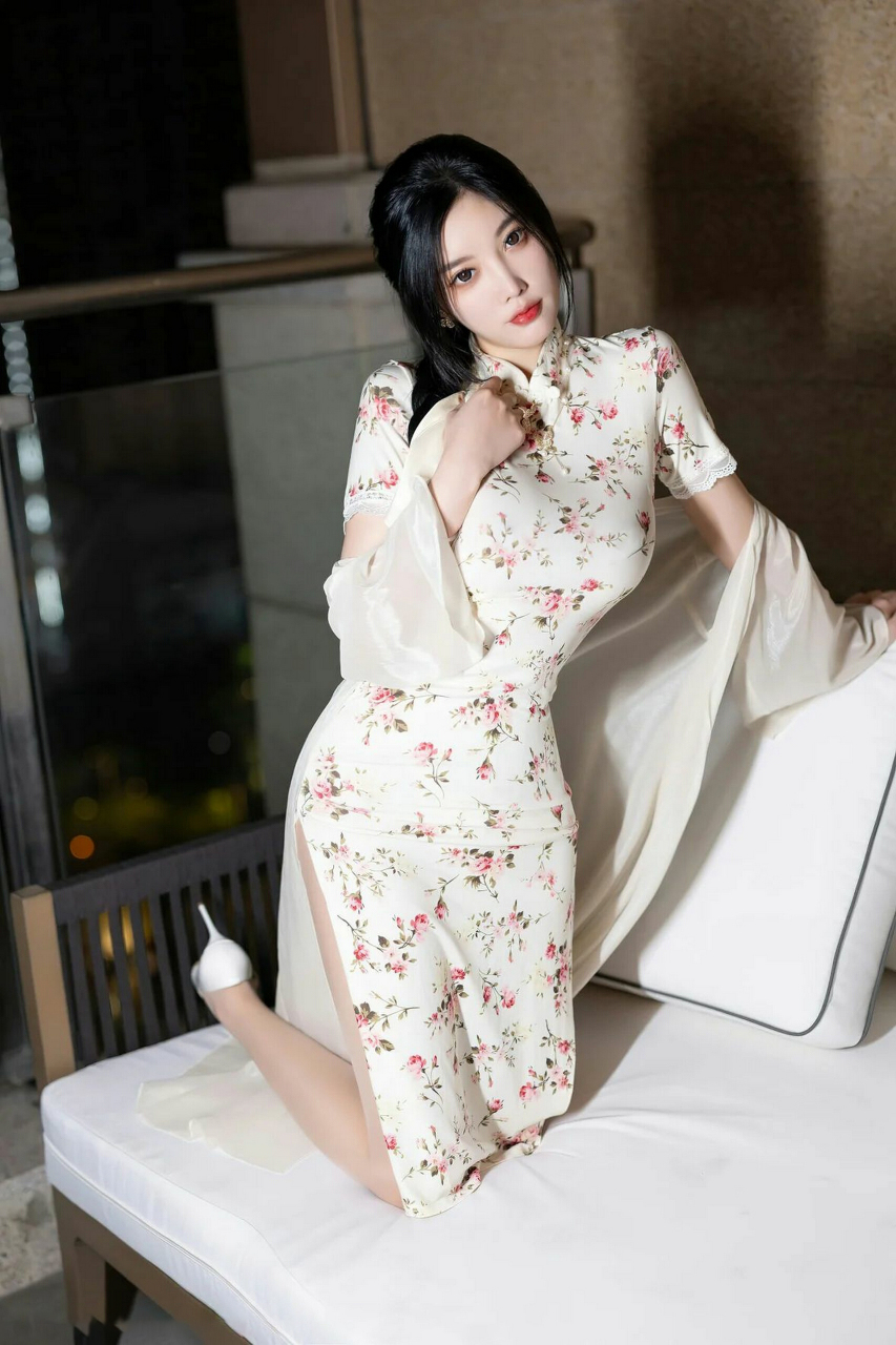穿着白色碎花旗袍,肤色丝袜,显得曼妙迷人.她的微笑和自信令人陶醉.