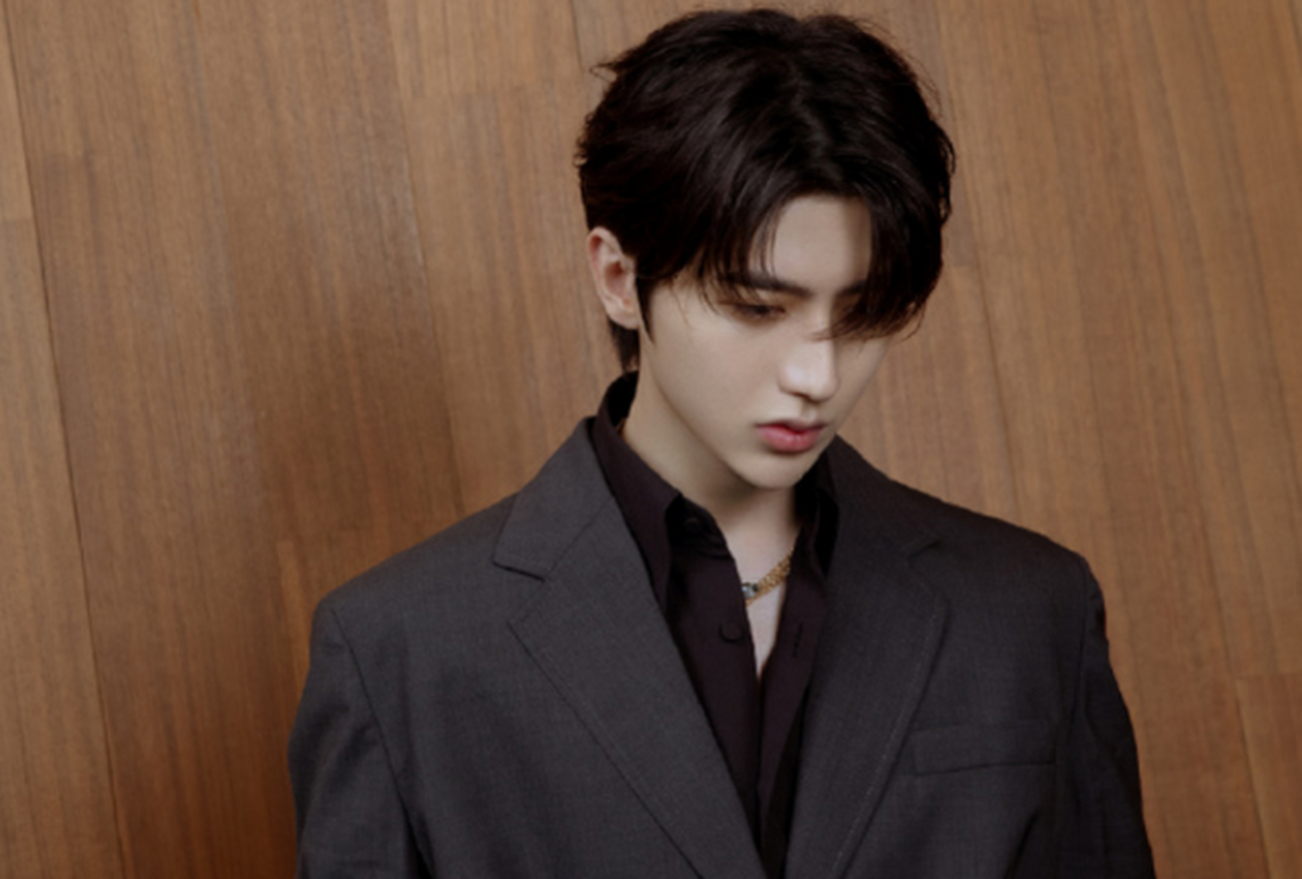 照片中,蔡徐坤侧梳刘海,穿着深棕色内搭衬衣,外穿灰色西装外套,身姿