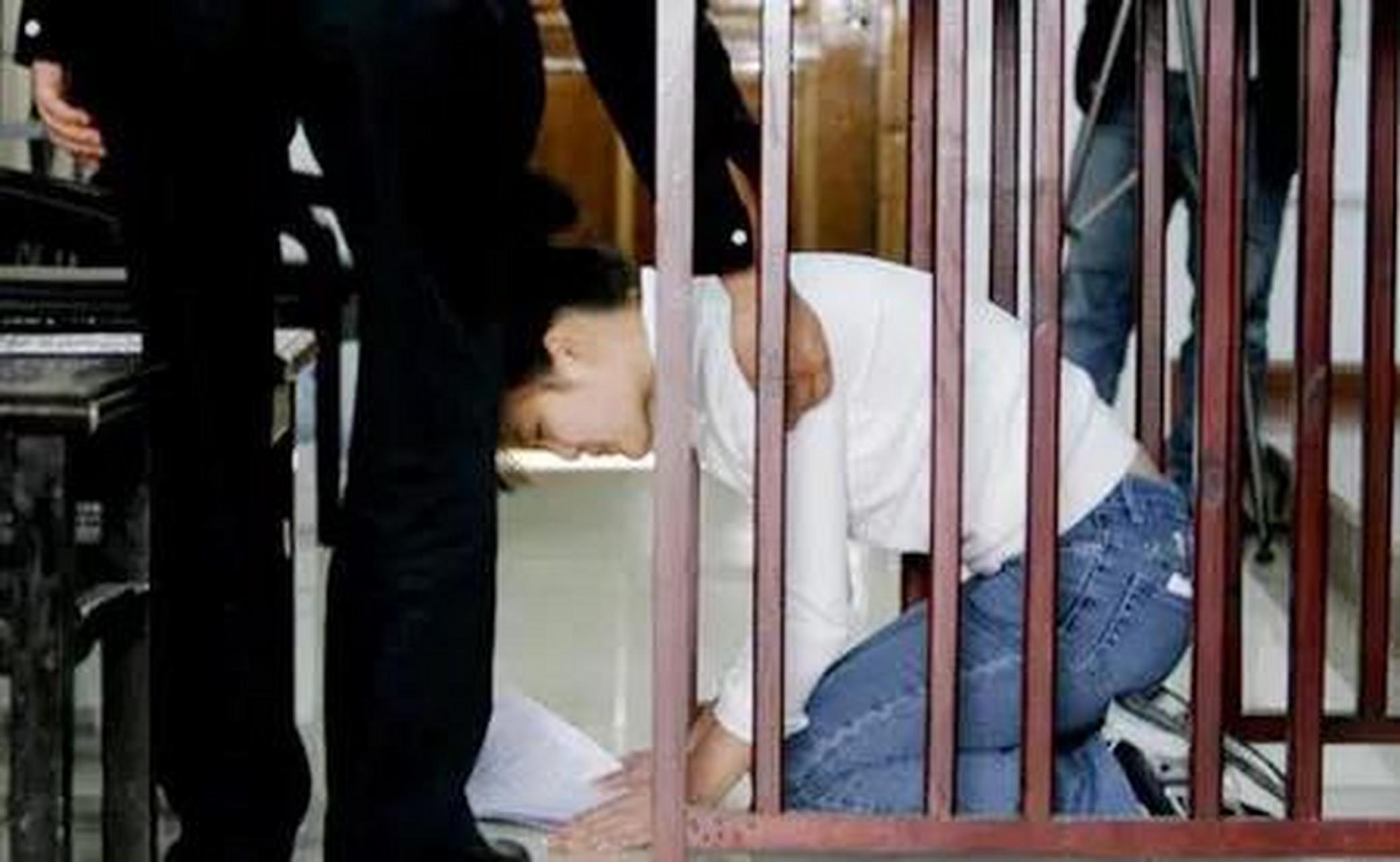 女犯罪嫌疑人张超站在一审被告席上,她梳着发髻,穿着白色的上衣,下穿