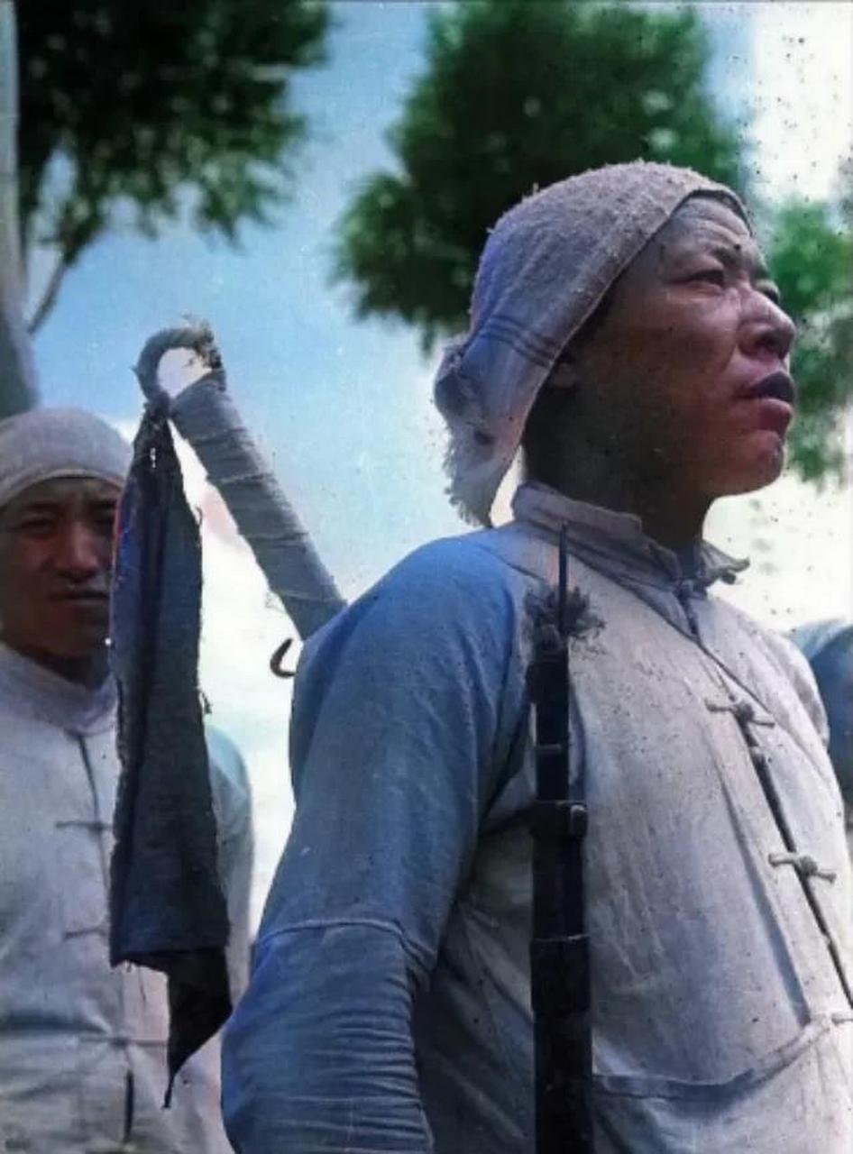 照片中前面这位民兵背着一把大刀,手执一把步枪