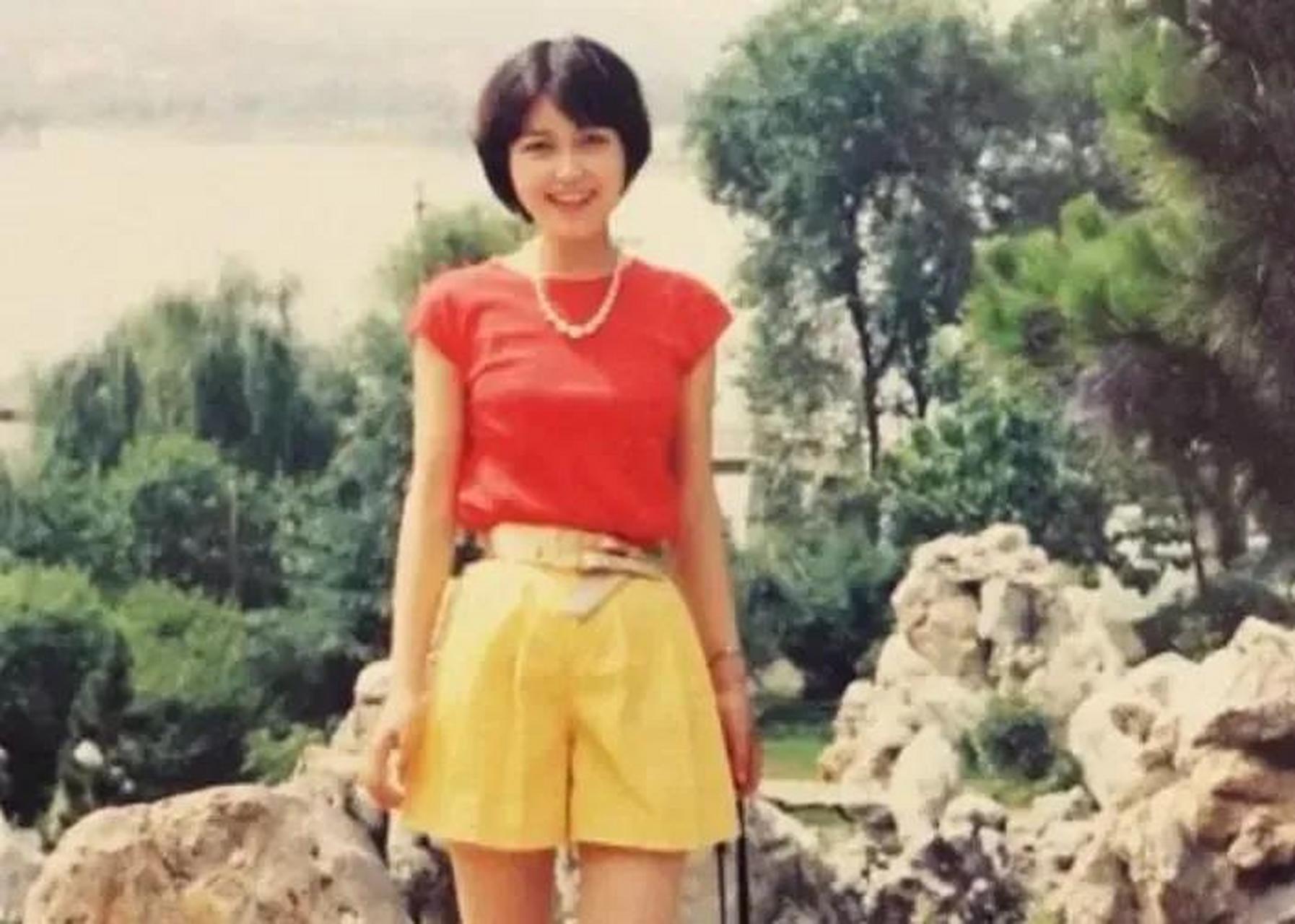 上世纪80年代,一位穿着红色上衣,黄色短裙的短发女孩在湖边假山前留下