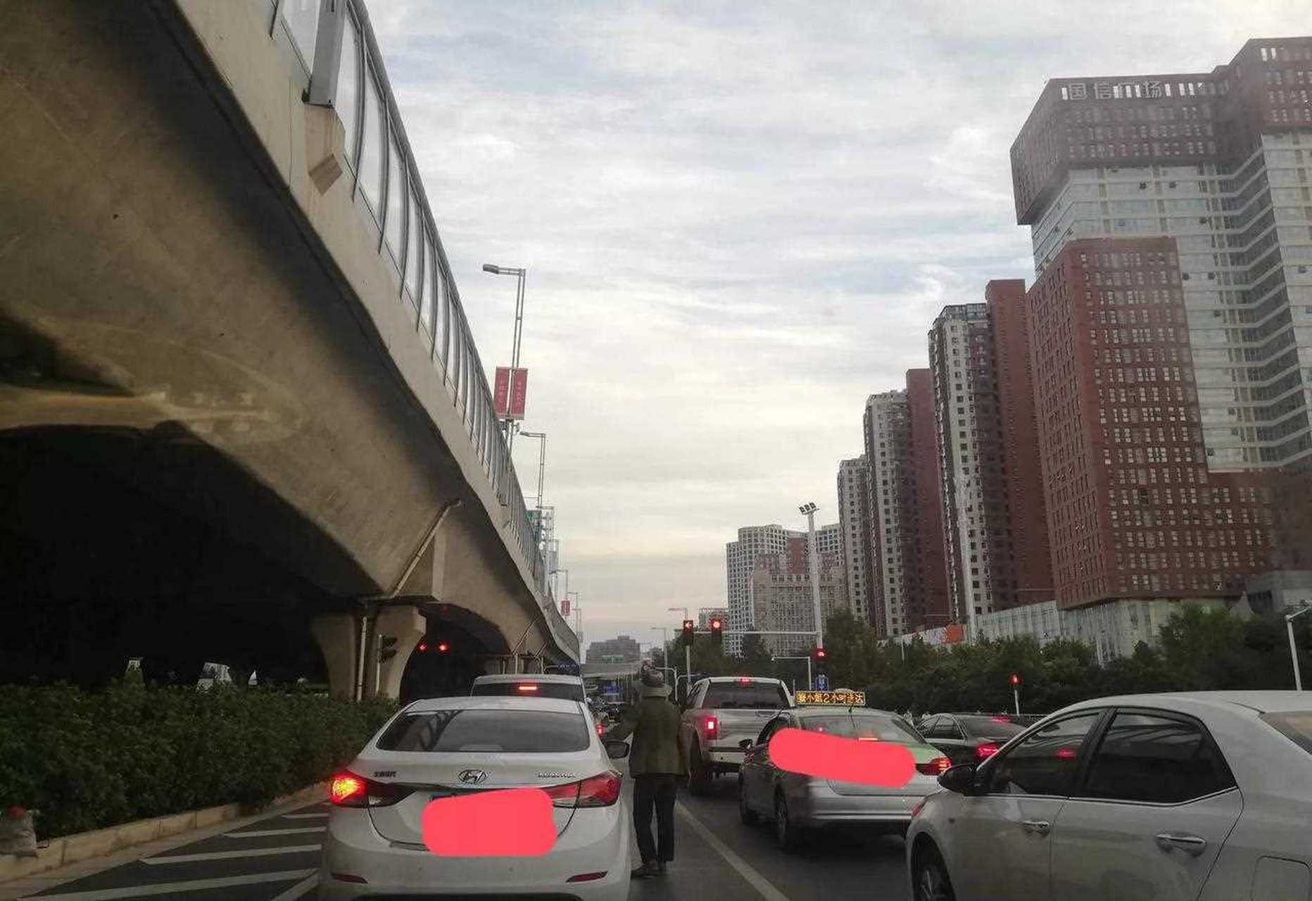 去天泽街吃云南石锅鱼,经过中州大道与东风路等红灯,看见有位穿着破旧