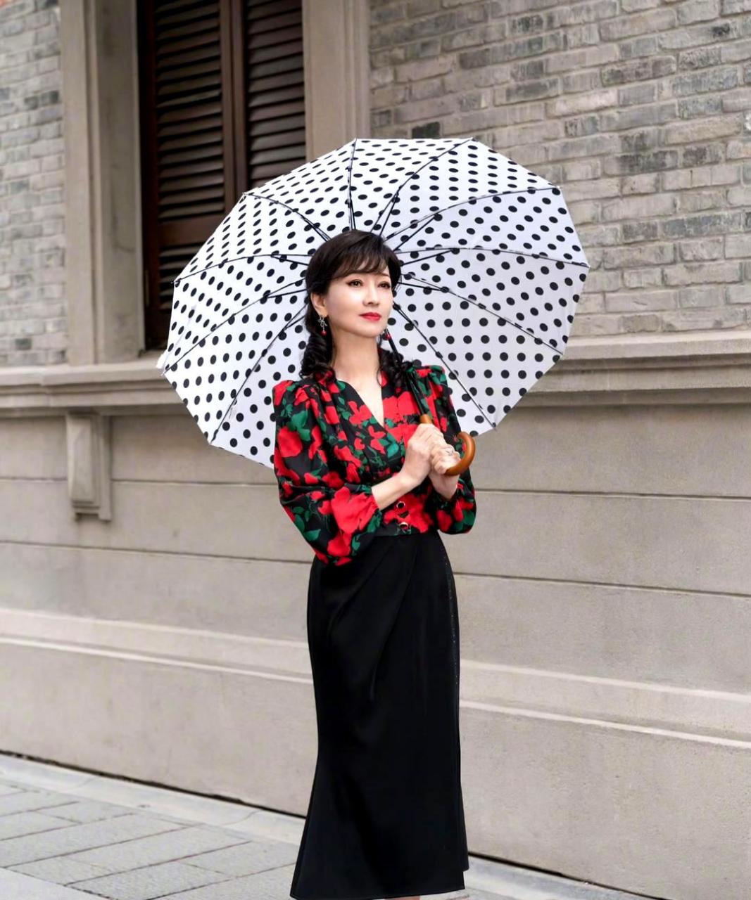 赵雅芝穿着大花朵复古衬衫,搭配黑色长半裙和红色高跟鞋,显得优雅而富