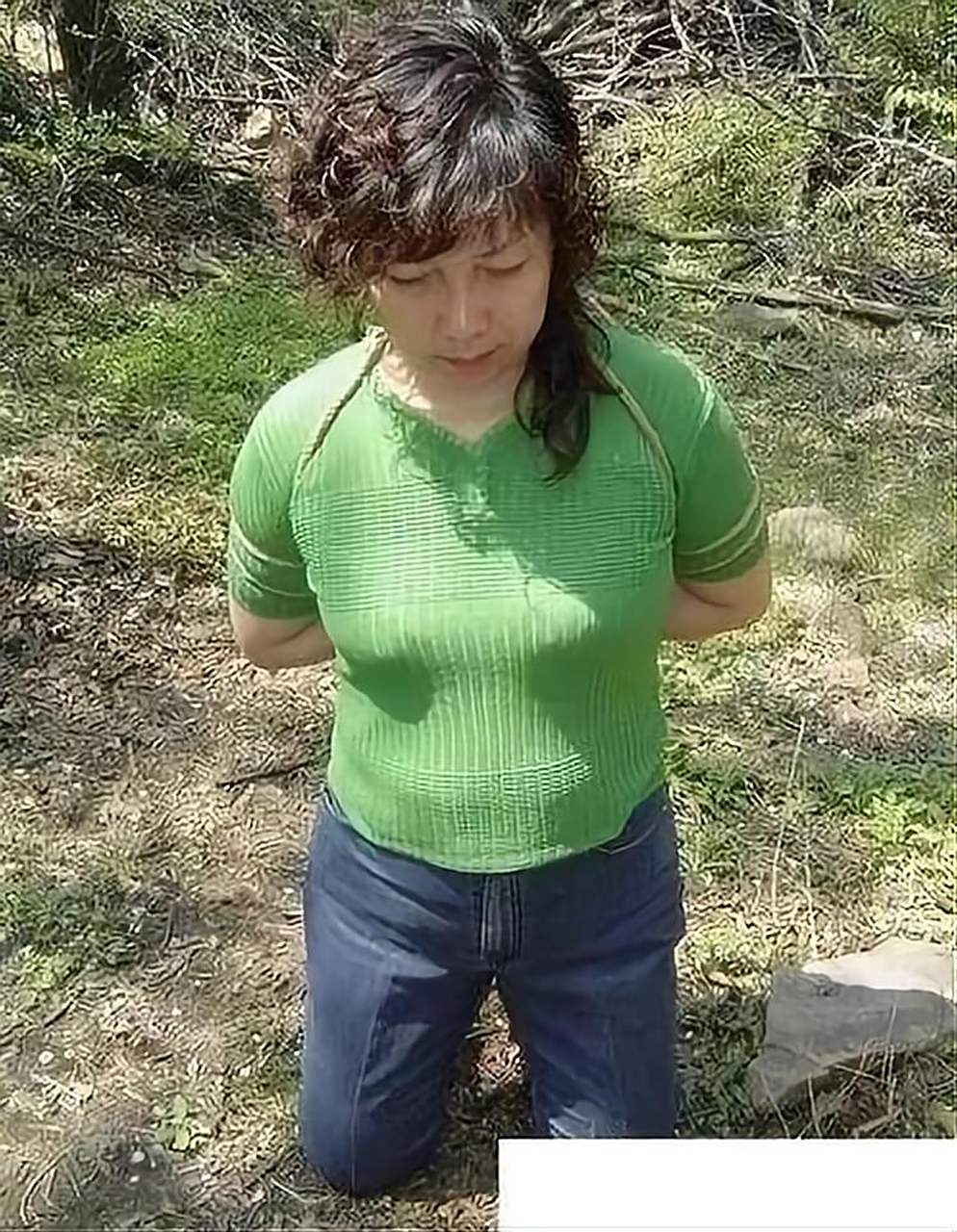 90年代被绑在绳子上的女犯人照片,镜头下的她头发泛黄,绿色紧身毛衣