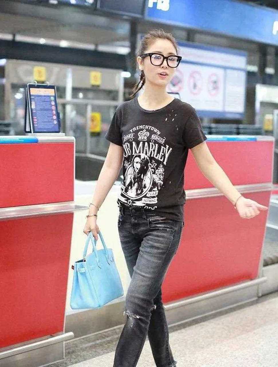 林心如机场街拍,卡通t恤配破洞牛仔裤,戴眼镜更显文艺范