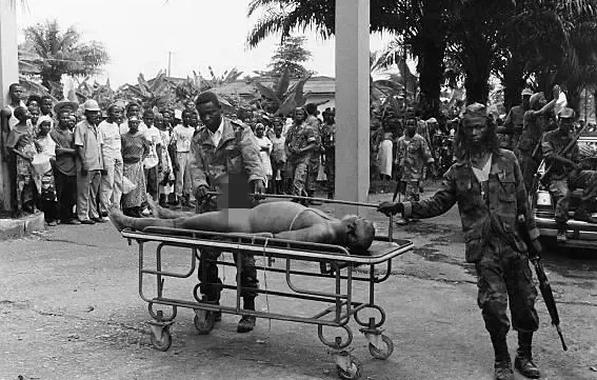 1990年,非洲暴君多伊,被公开处决后,一张罕见的留影,照片中一个士兵手