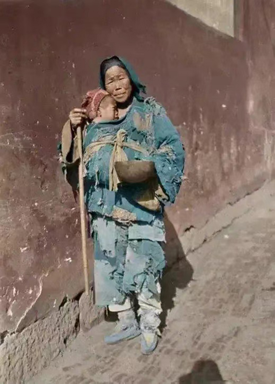 1917年,一位穿着破旧衣服的老妇人,拄着一根拐杖,手里拿着一个大碗,在