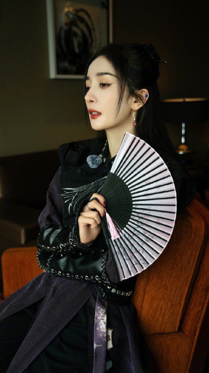杨幂的一组中国风侠客造型照片,杨幂身穿黑色紧身衣,手持古扇半遮面