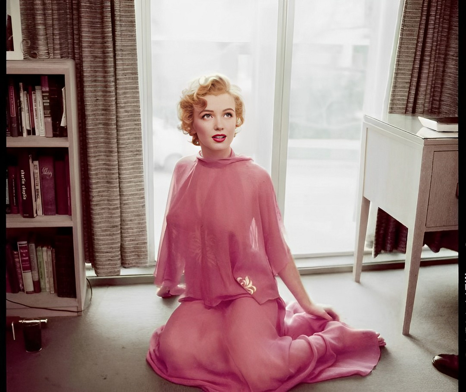 1950年,女神梦露穿着粉红色雪纺连衣裙阅读.