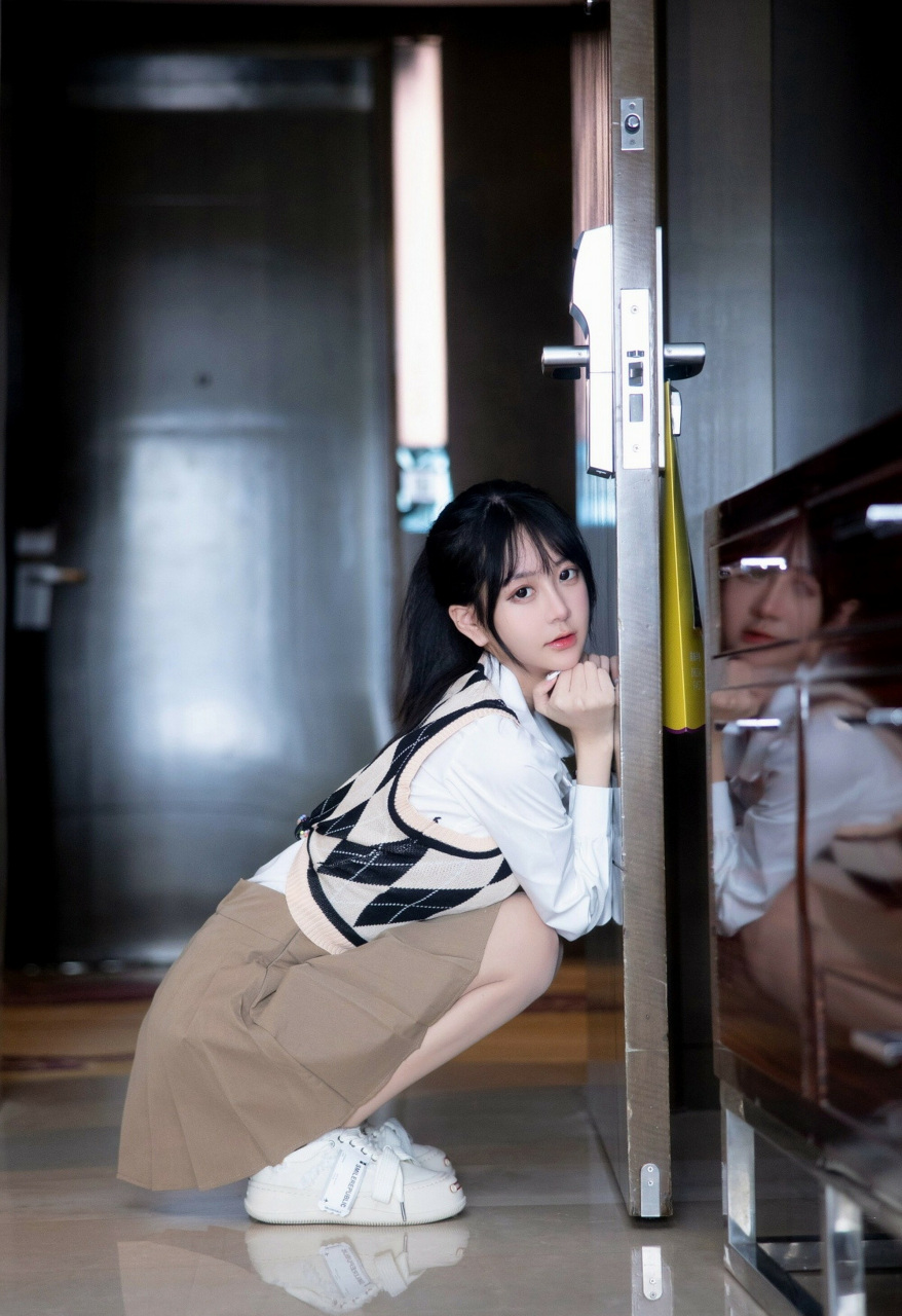 在室内门口,女孩儿静静蹲坐着.