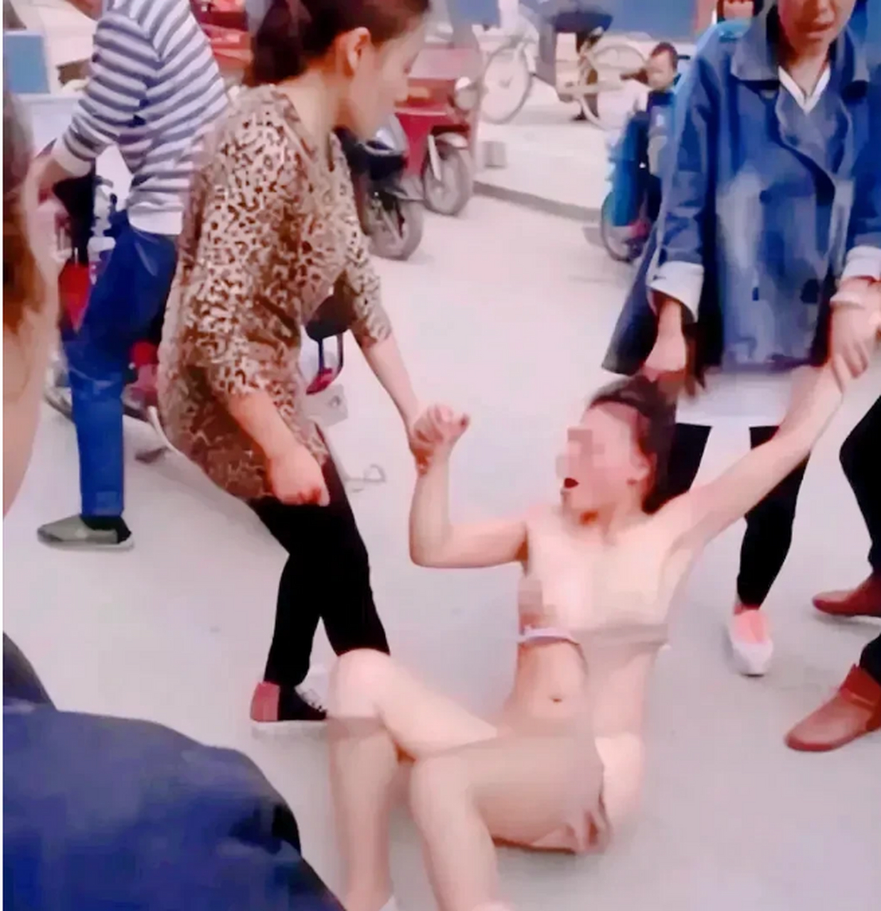 这一幕场景不堪入目,小三衣衫不整,躺倒在地上,几个女人拉着她的手