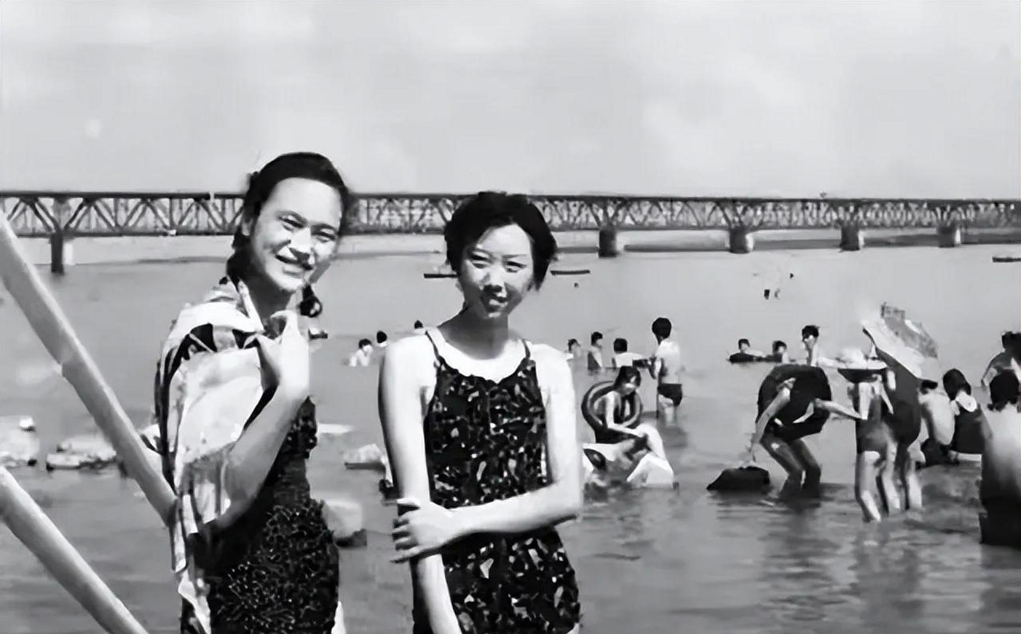 80年代,杭州钱塘江边两位穿泡泡泳衣的小姐姐,远处是正在钱塘江里游泳