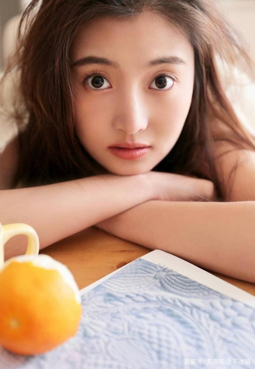 橘子少女 身穿暖黄色吊带外搭同色系针织开衫的少女,剥开橘子皮,手上