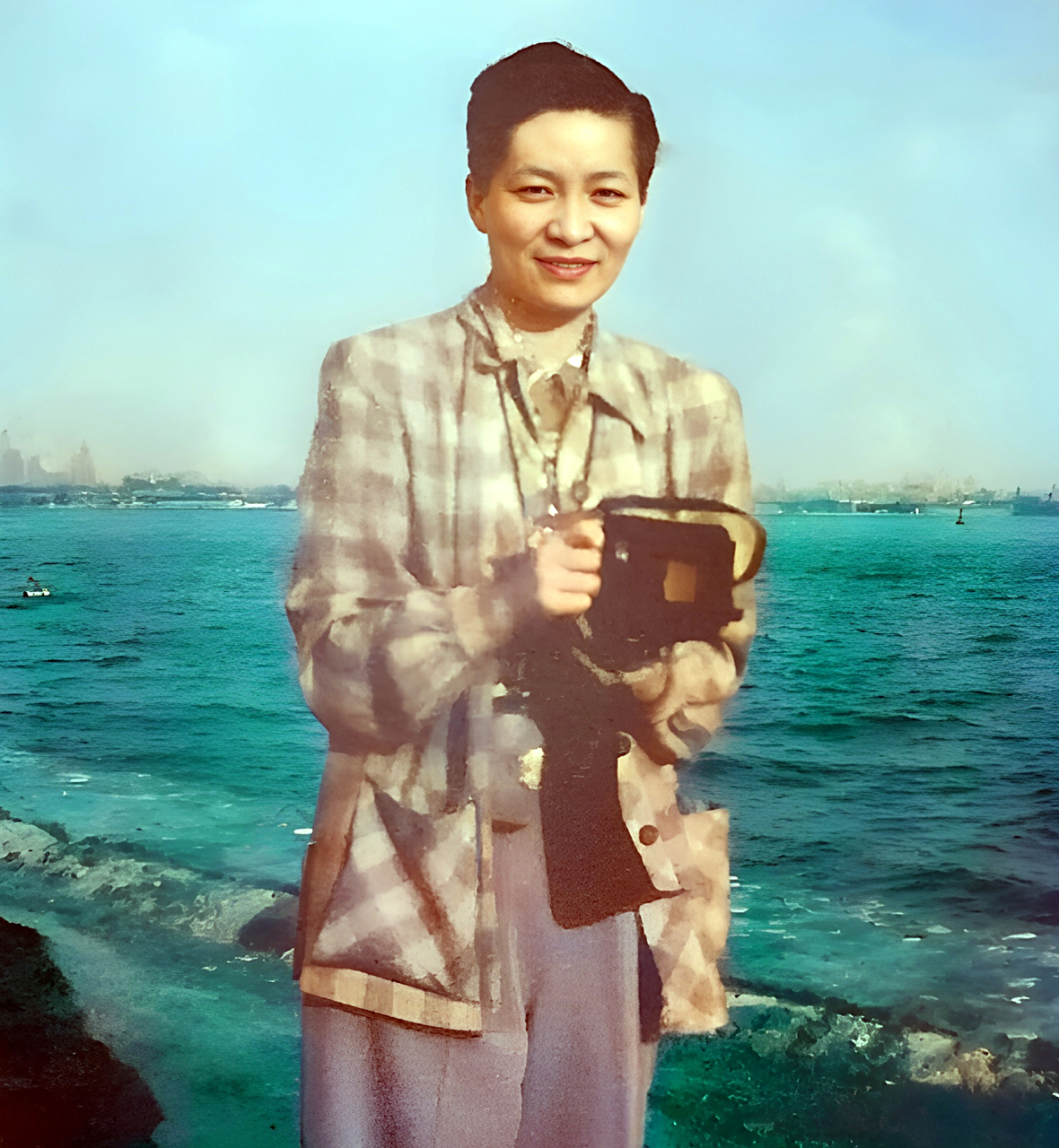 这位站在海边,手持相机的女子名叫伍锦霞.伍锦霞从小喜欢电影与粤剧.