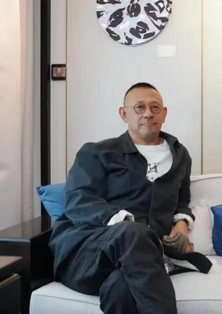 照片中,姜文和姜武还有姜可欣坐在沙发上合影,他穿着黑色衣服,头芳趑