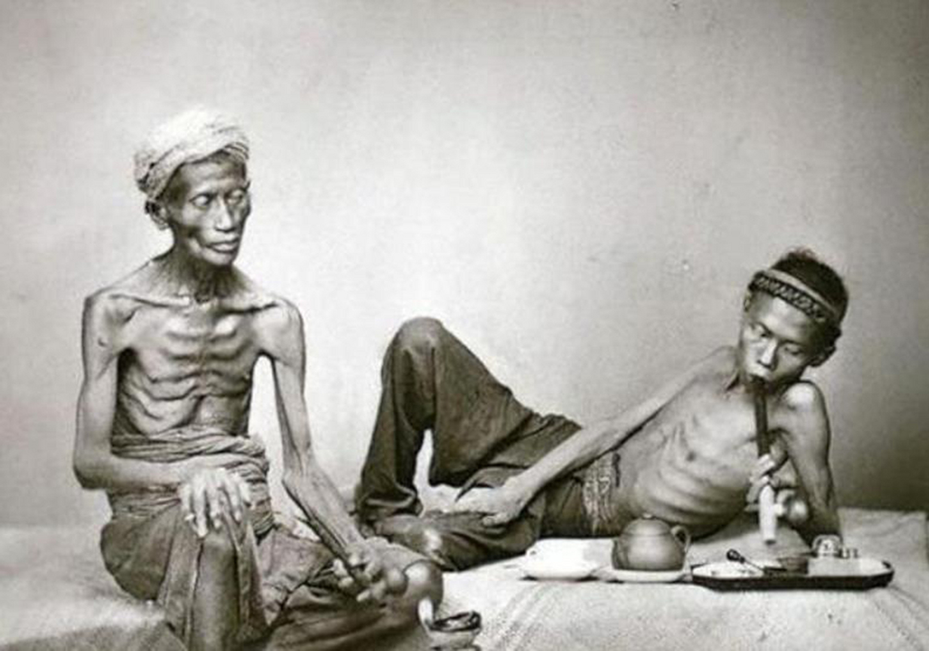 清朝末年的一张照片,两个抽大烟的男子 看起来特别瘦削,甚至可以