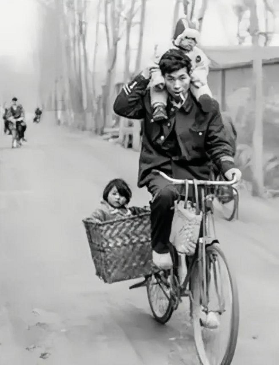 上世纪80年代,一个年轻父亲骑着自行车驮着俩孩子,车技高超,就像玩