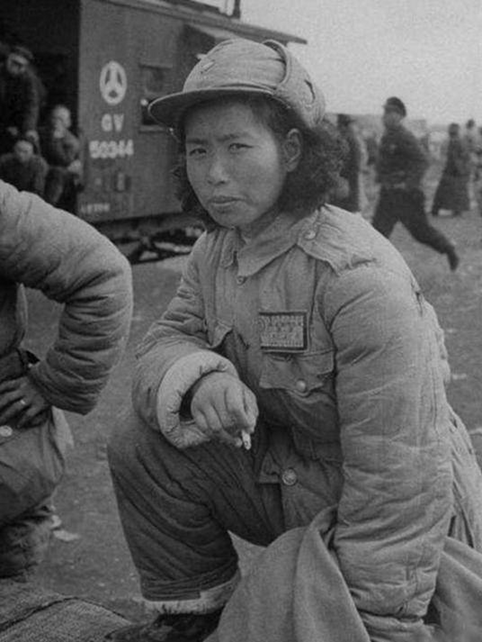 历史老照片:一个女战士单膝跪在地上,手里掐着烟