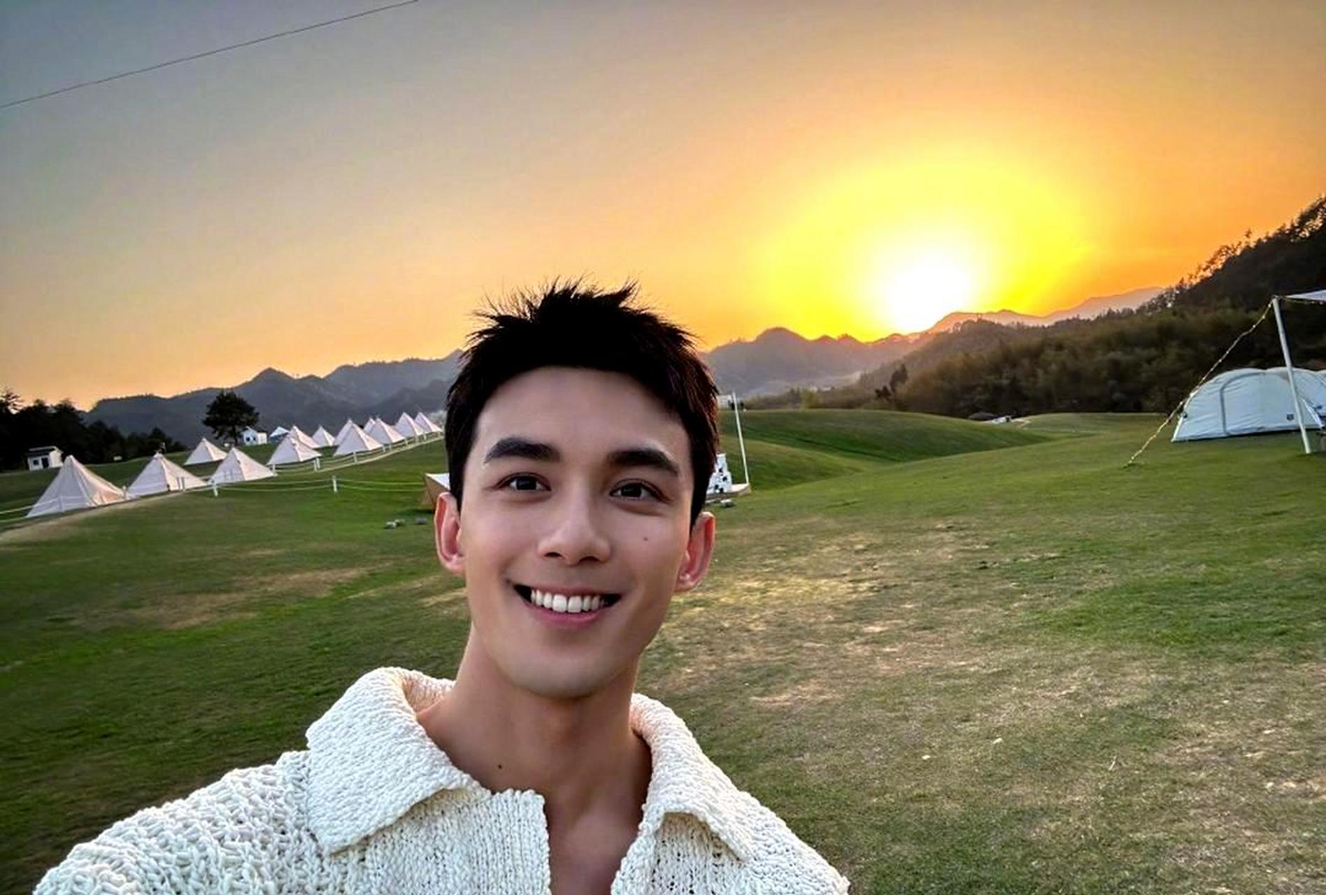 吴磊在夕阳余晖下拍摄自己收工的照片,笑容中露出洁白的牙齿,阳光下更