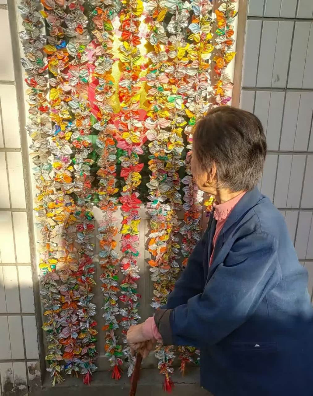 奶奶的门帘是用零食包装纸制成的,在阳光下闪闪发光