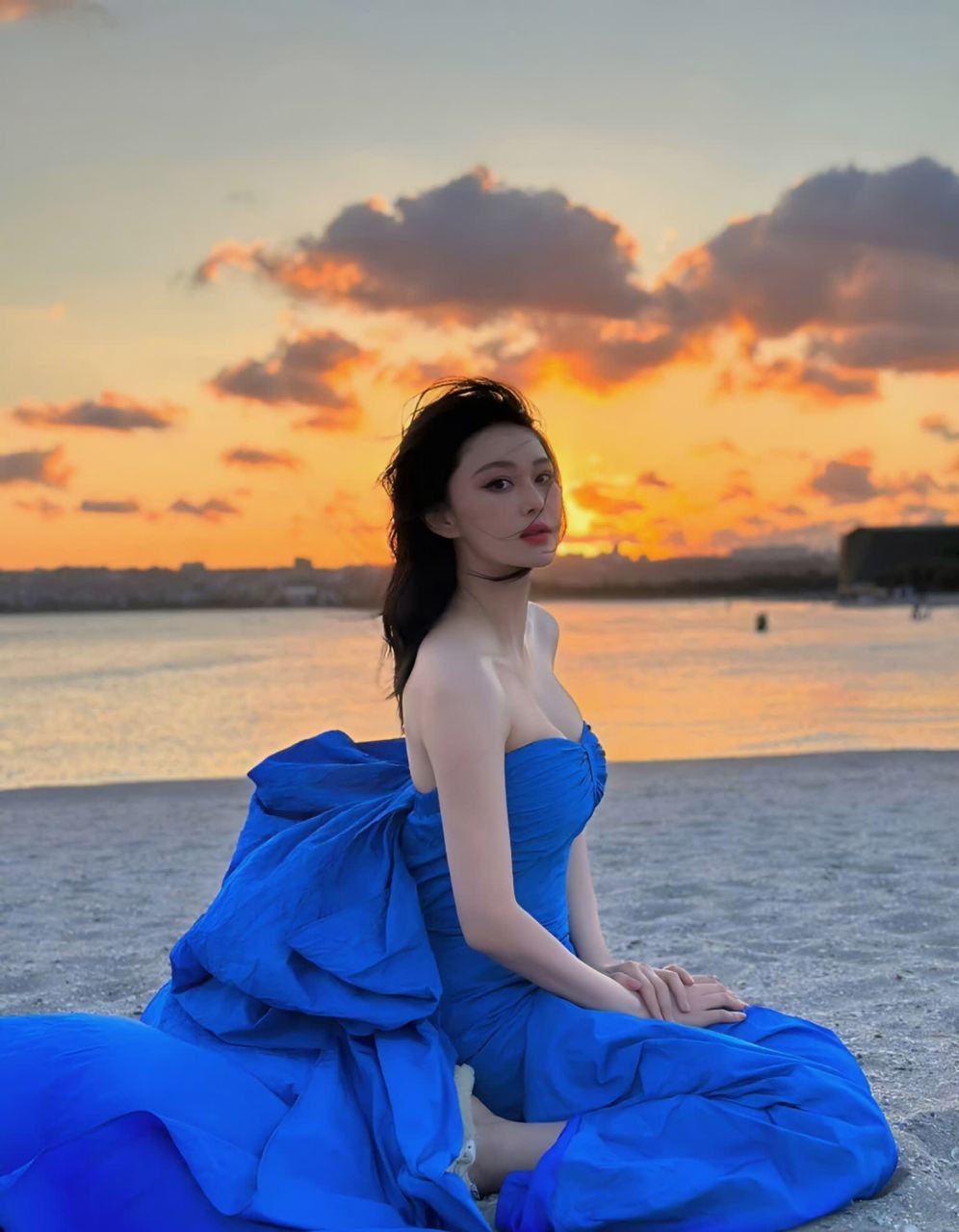 张馨予身穿蓝色抹胸连衣裙漫步在沙滩上.