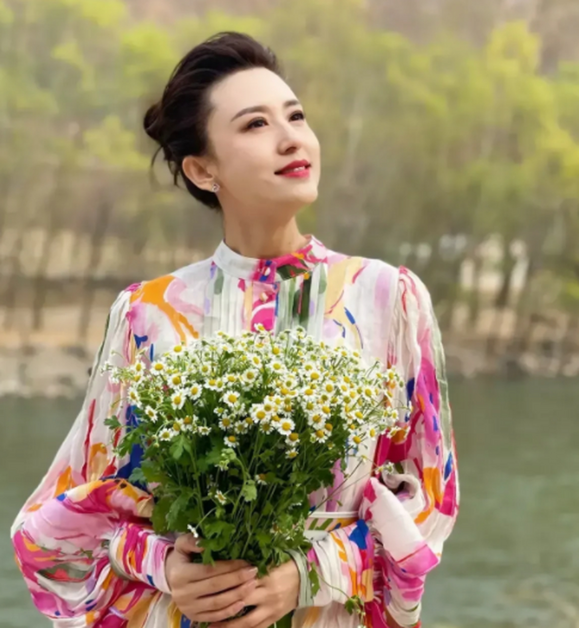 央视著名主持人张雷非常喜欢在户外拍照,她穿着一条带大花的长裙,手里