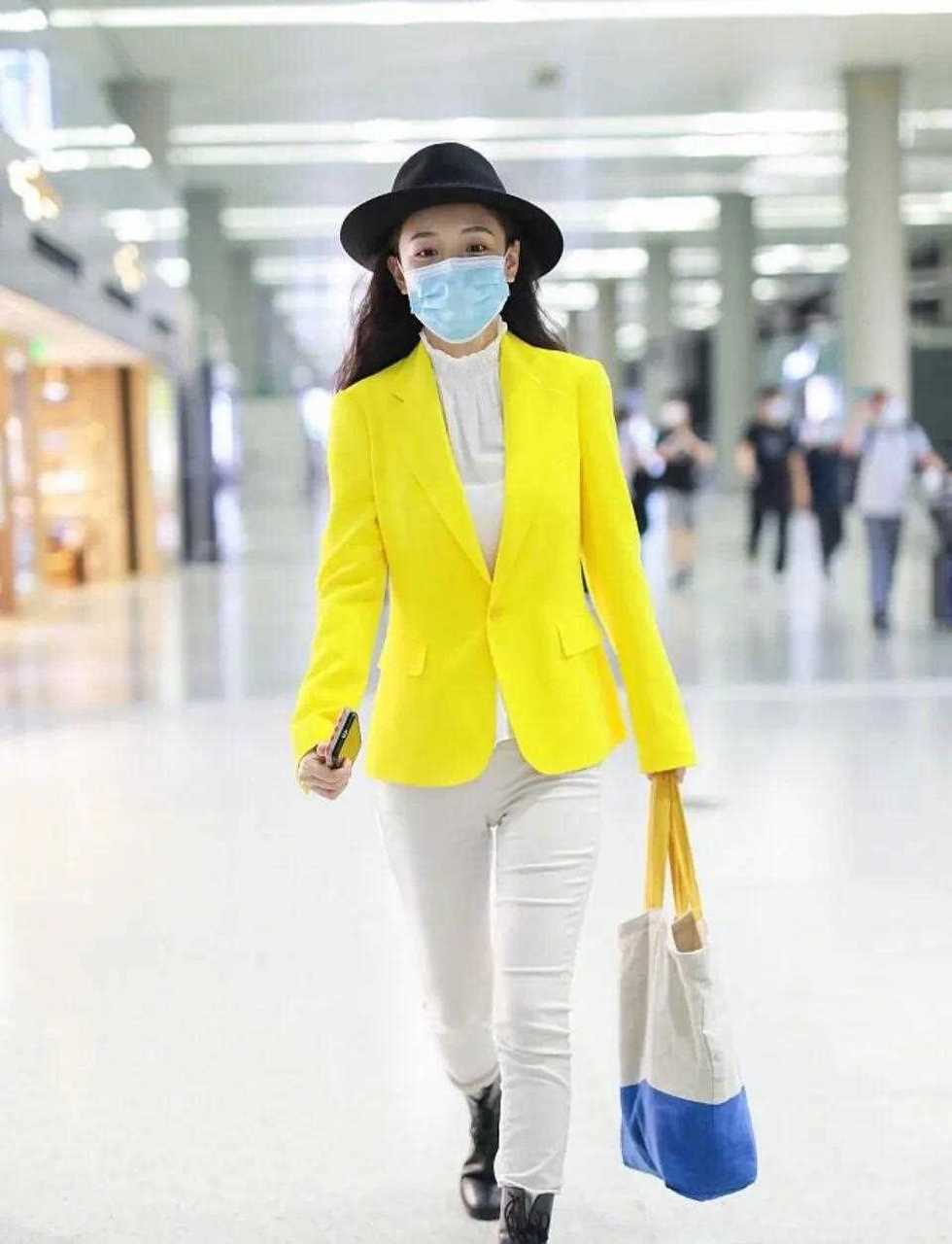 【吴倩机场造型】荧光亮黄外套搭配一身米白色内搭和外加的黑帽,不过