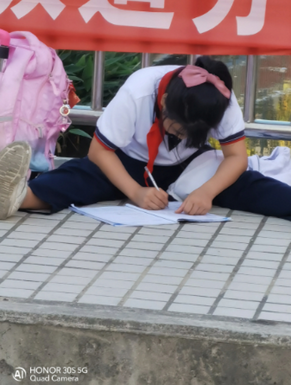 刚刚在惠州大亚湾澳头光亚小学门口看见一个小朋友席地坐在马路边上写