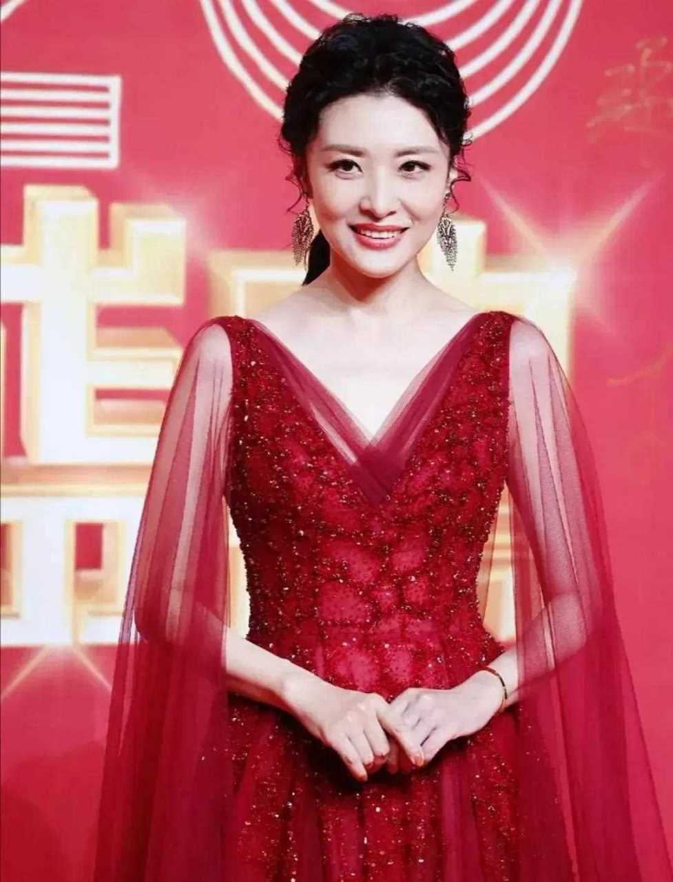 著名主持人周涛出席活动,穿着一身红色v领薄纱礼服,扎着马尾辫,戴着