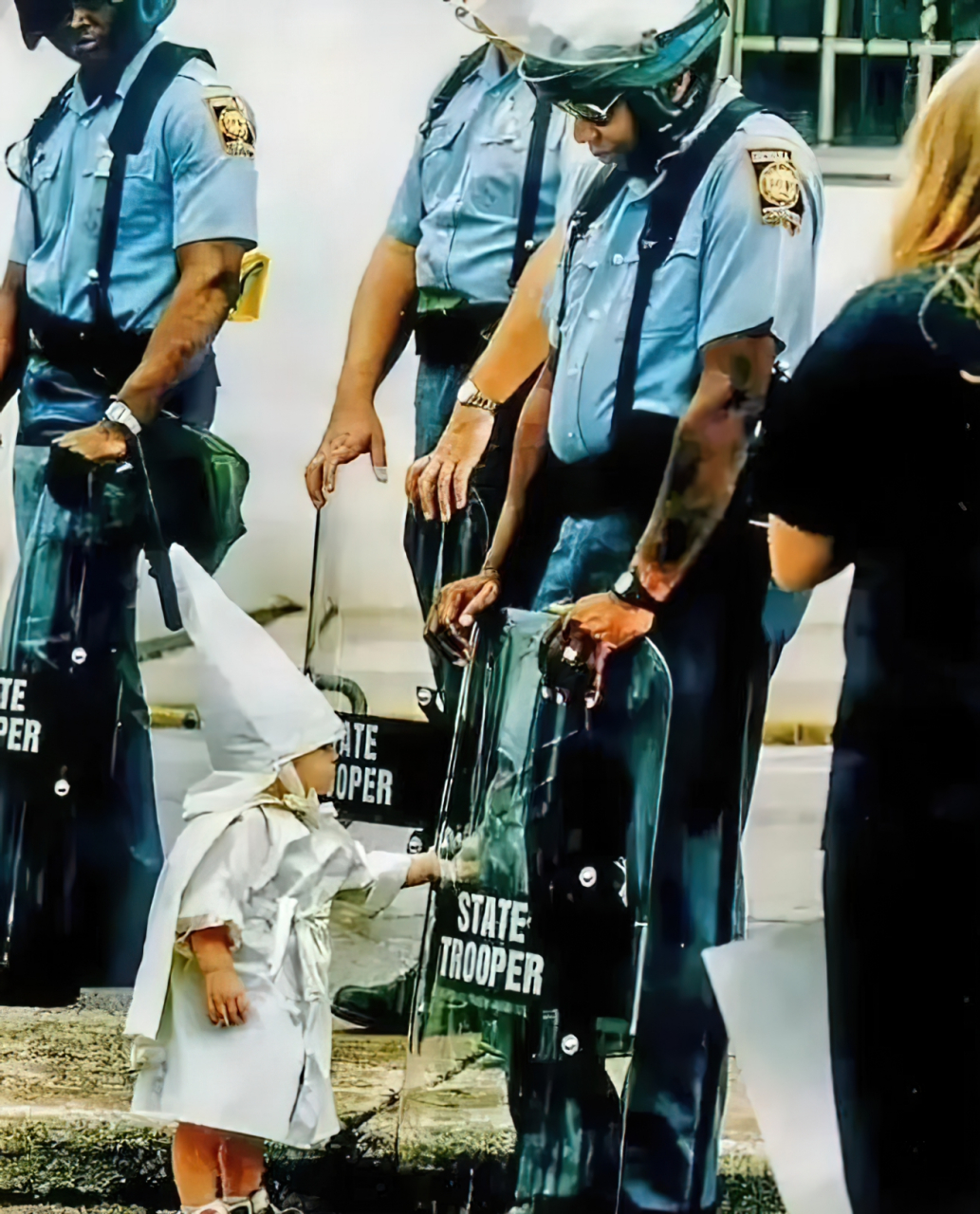 1992年,美国三名警察和一个戴白色尖顶帽子的小孩出现在镜头中,尽管