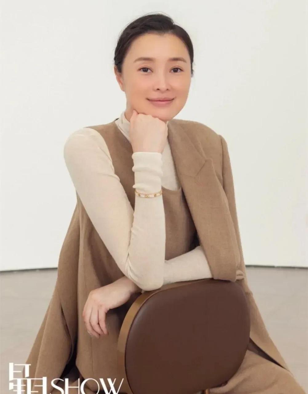 吴越穿着一袭卡色背心连衣裙,外搭同色小西装外套,内搭米色高领针织