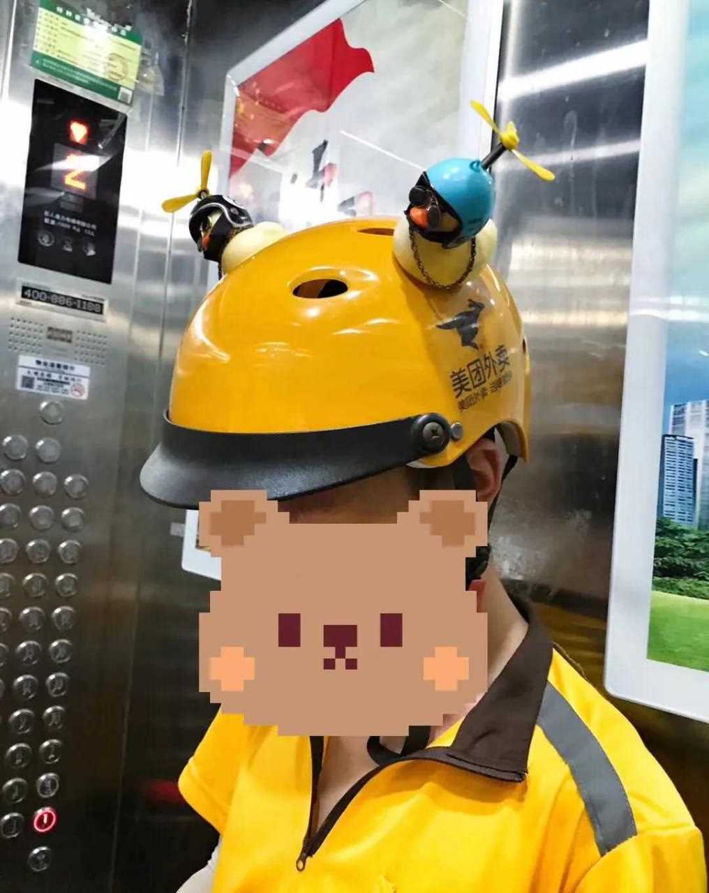 读者朋友在电梯里遇到一位美团外卖小哥,头盔上一边一个小黄鸭,还带着