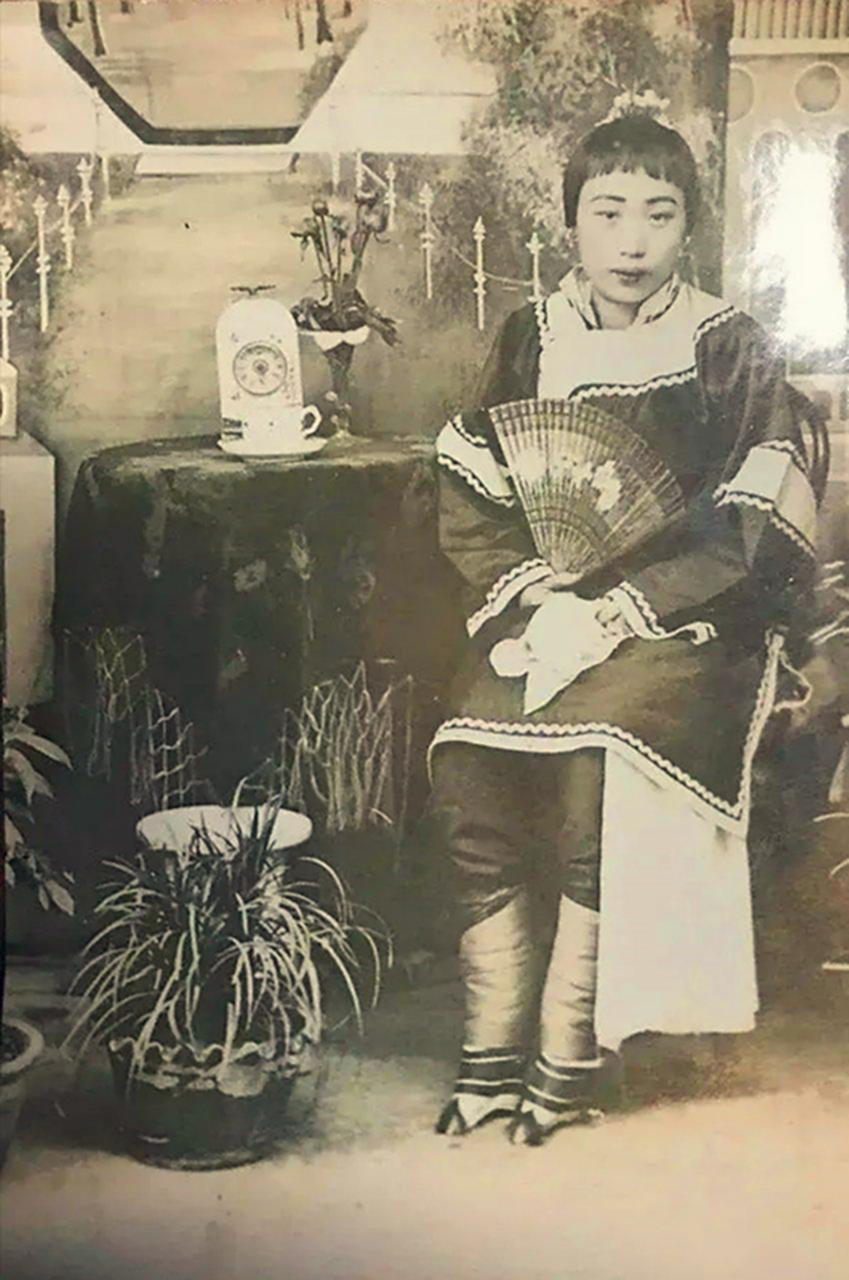 历史老照片,晚清一大户人家的女子,她穿着斜襟外加小袄裤,手里拿把