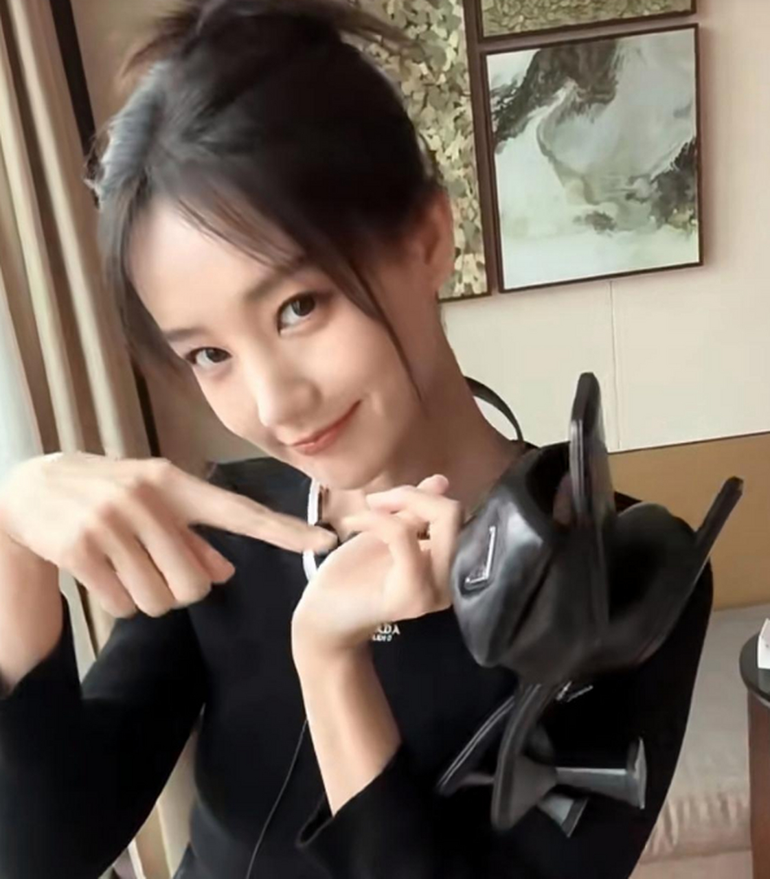 李一桐在窗户边美美自拍,手里拿着新的高跟鞋,表情甜美扮可爱,大眼睛