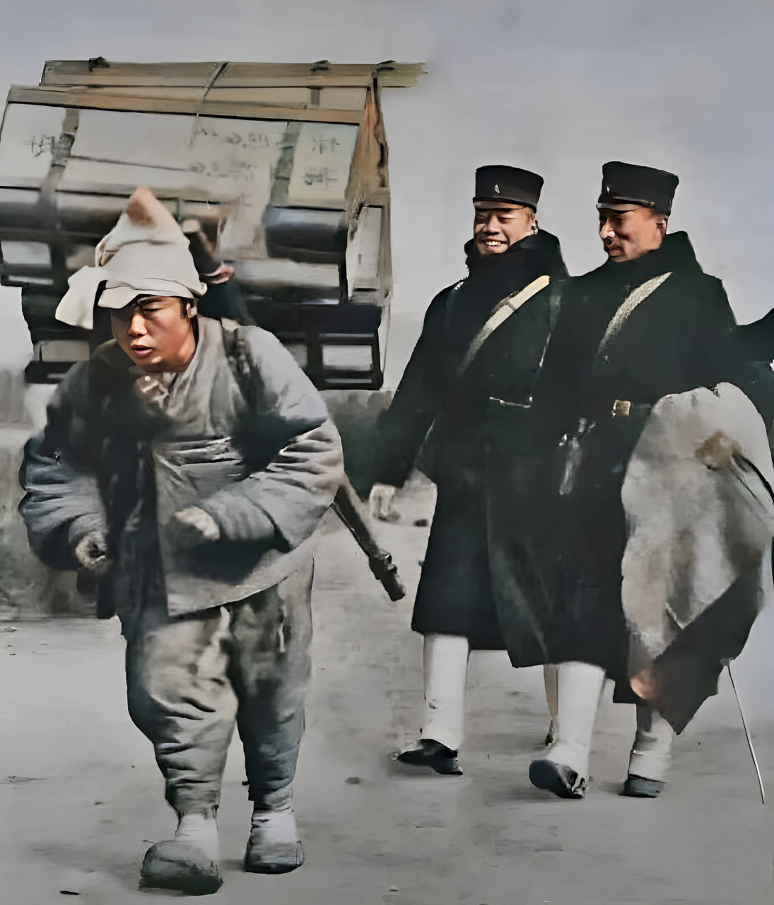 1905年,日俄战争期间,两位日本士兵有说有笑,一名男子在他们面前搬运