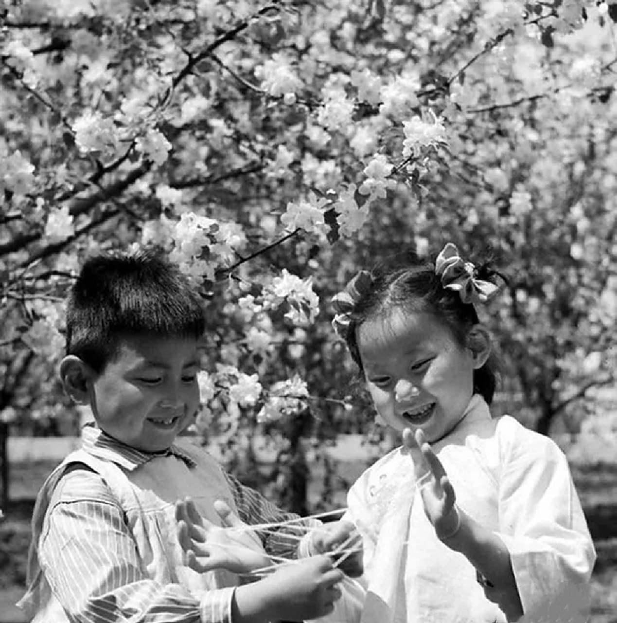 两个可爱的小朋友在玩翻花绳游戏,大家有玩过的吗?